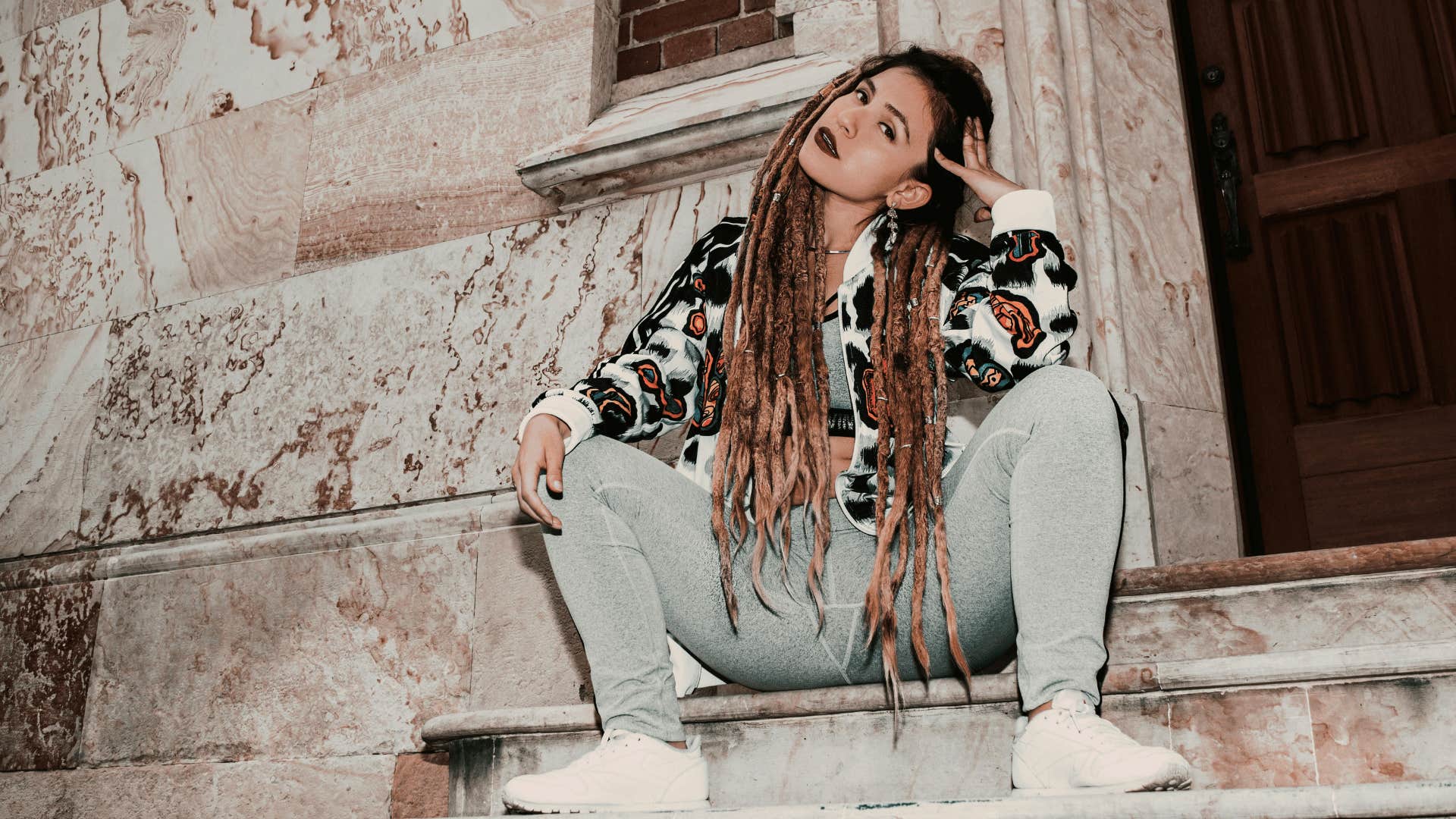 millennial woman sitting on stoop wearing sweatpants