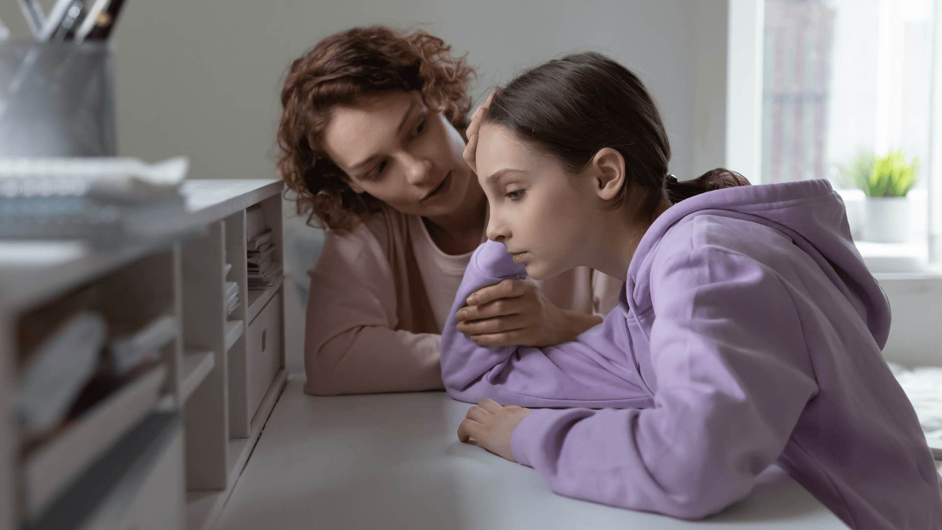 Upset teenage girl sitting next to her mother who can't pay tuition