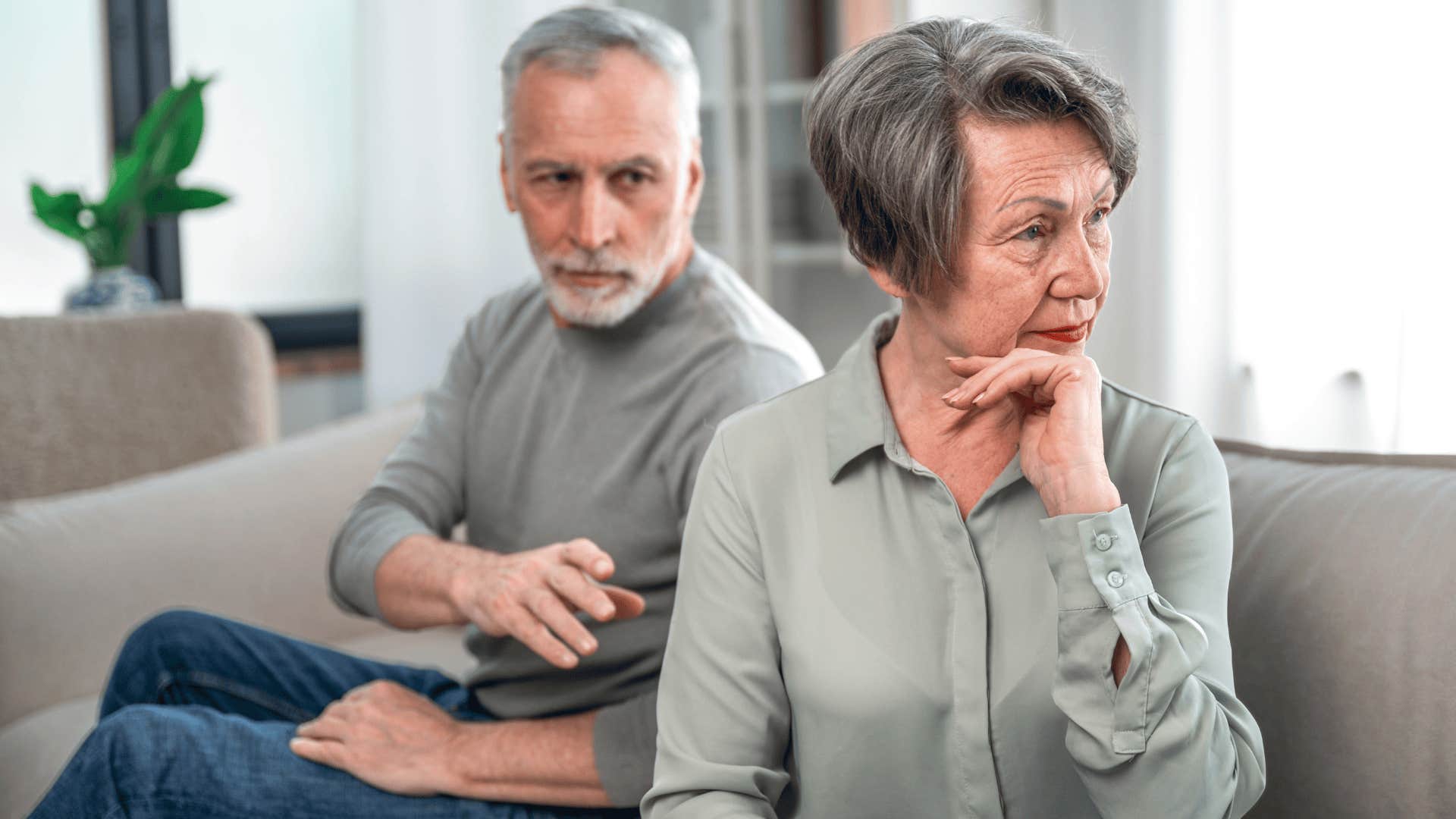 Older couple without accessible and comprehensive healthcare looking upset sitting on a couch together