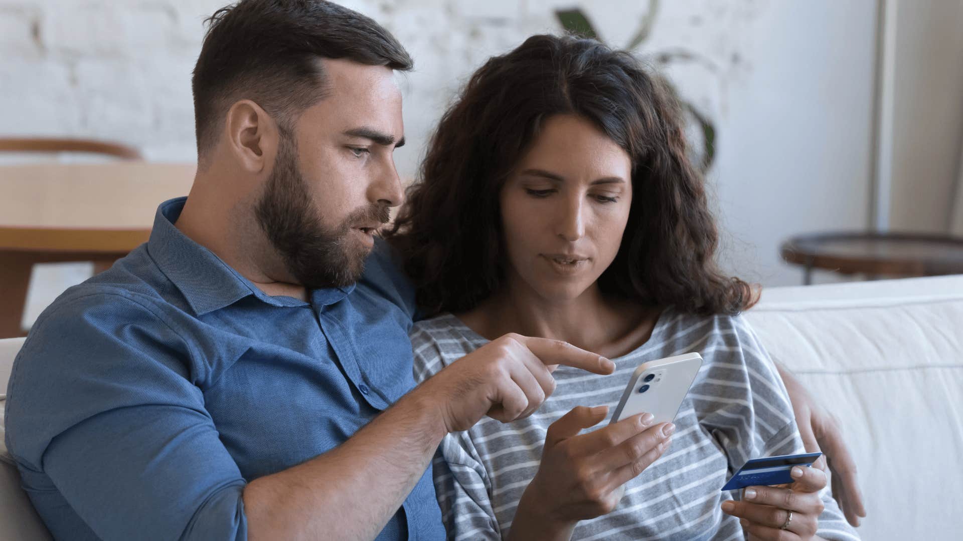 Upset couple with no investment opportunities looking at a phone and holding a credit card