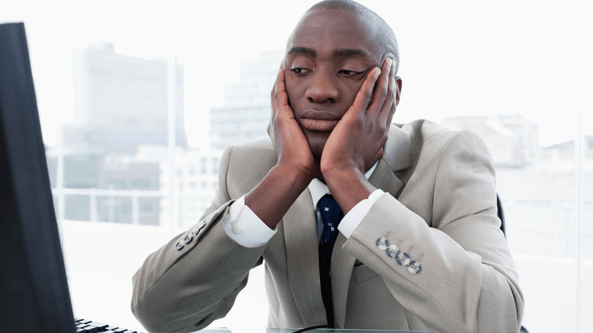 Bored man who can't retire sitting at his desk at work
