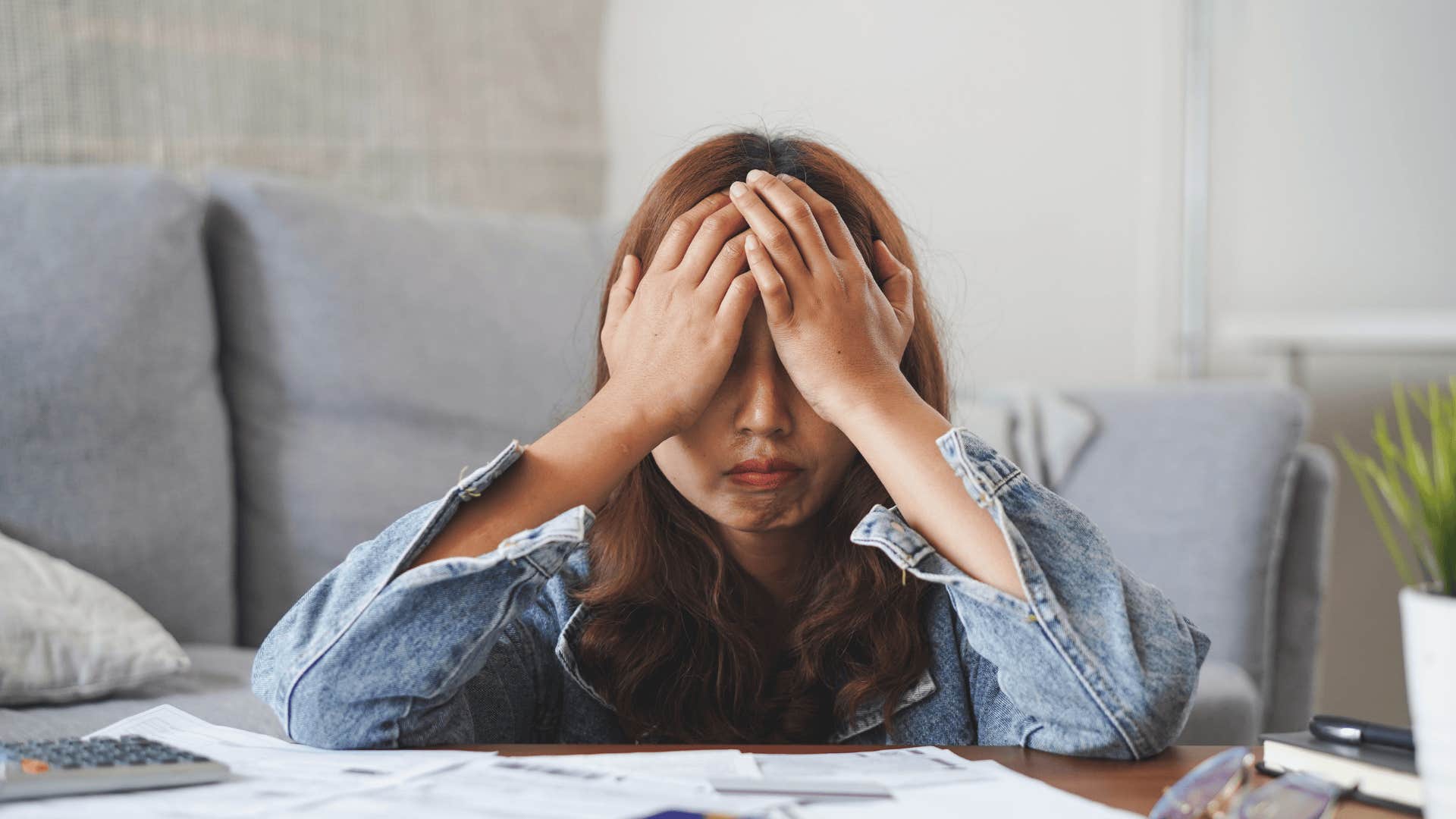 Upset woman holding her face in her hands will always worry about money