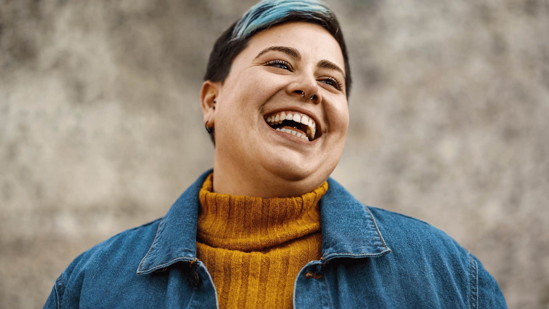 Gender fluid person laughing and looking away from the camera.