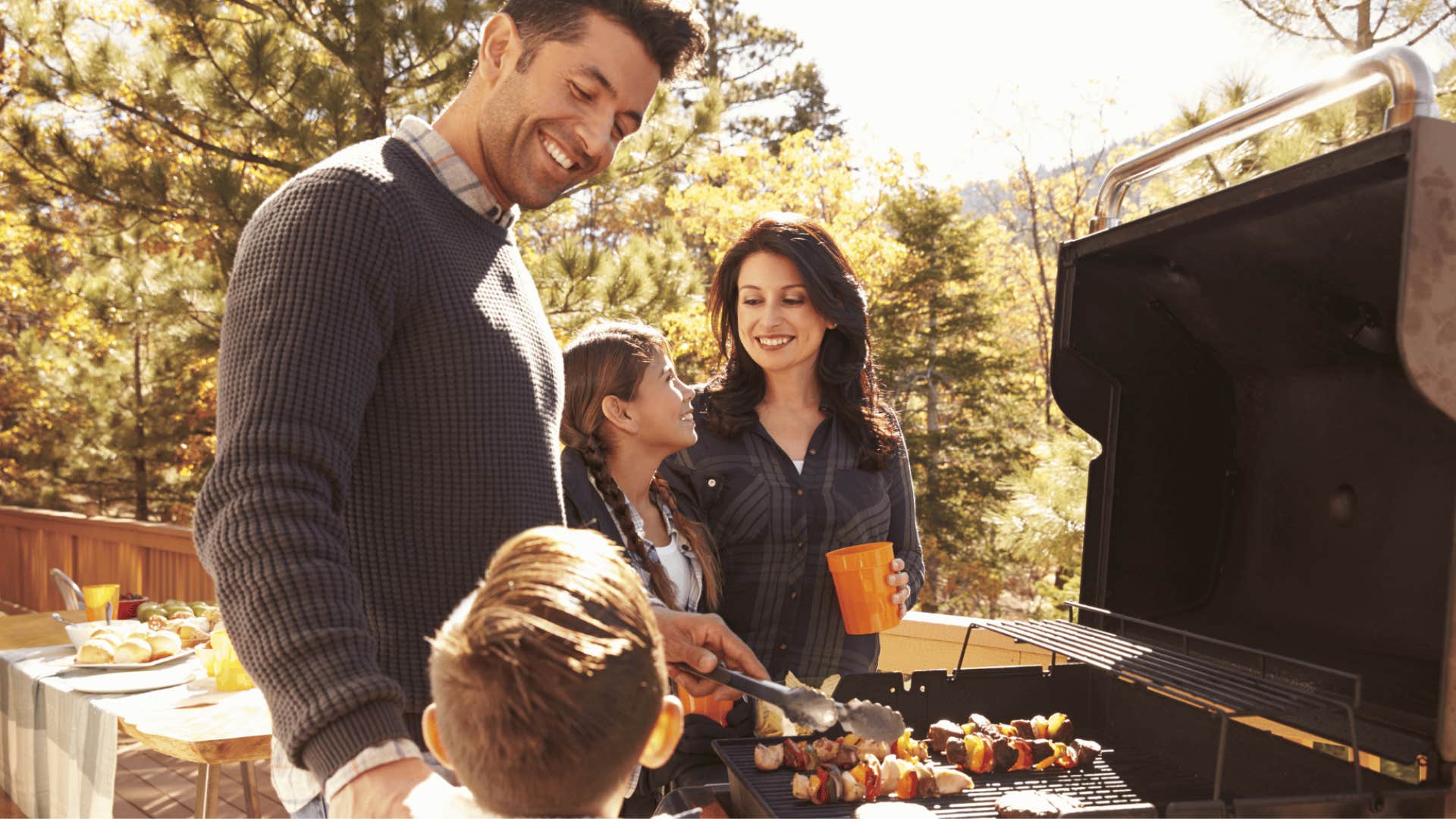 A family uses their grill outside.