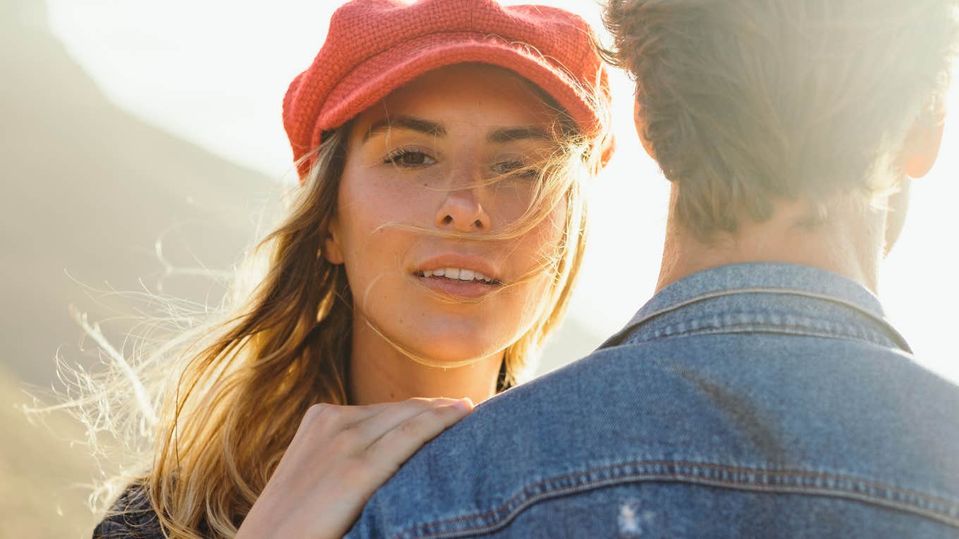 Woman in red hat looking over man's shoulder doing things after fight to keep together