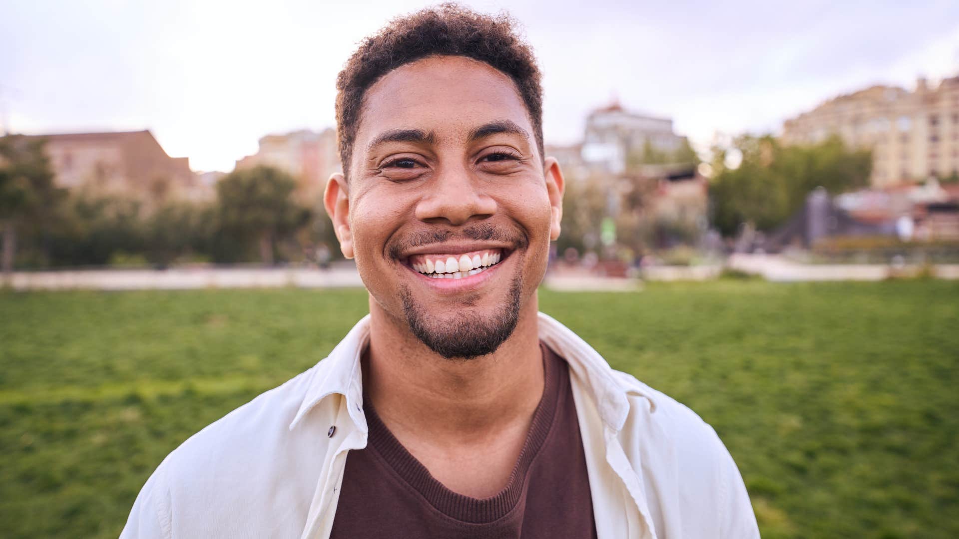 Emotionally resilient man smiling at the camera outside.