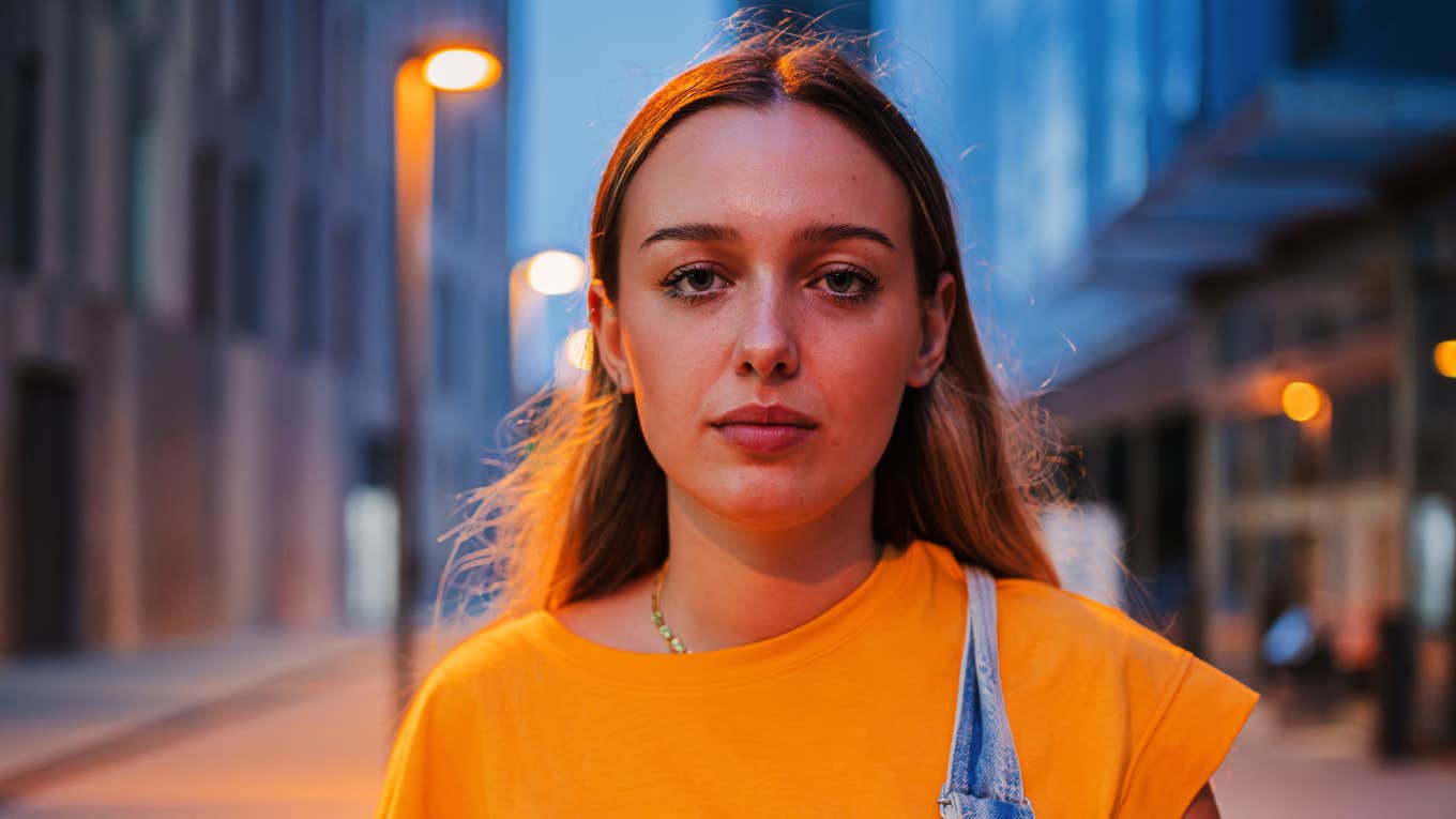 Traits That Give Off Bad Vibes Without Anyone Meaning To serious woman standing in the street at night giving off bad vibes