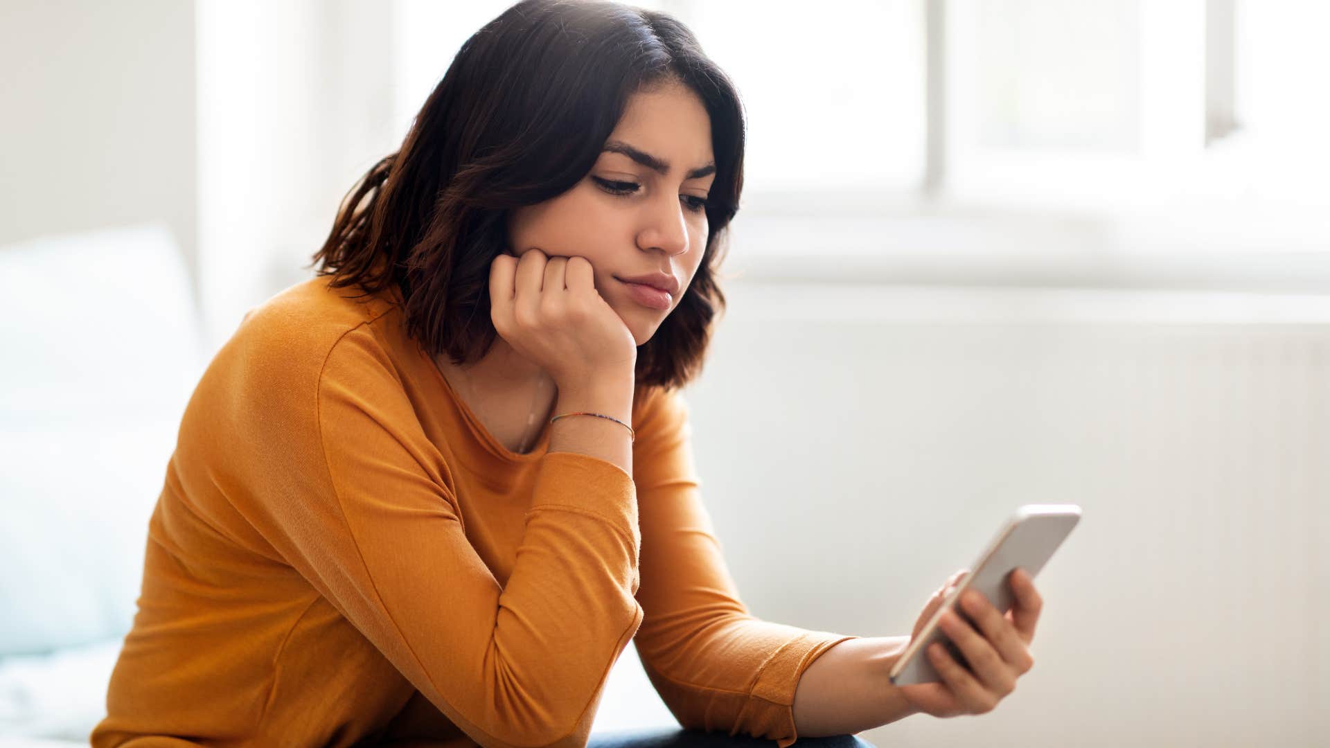 Woman thinking about how no contact isn't always the right solution looking at her phone.