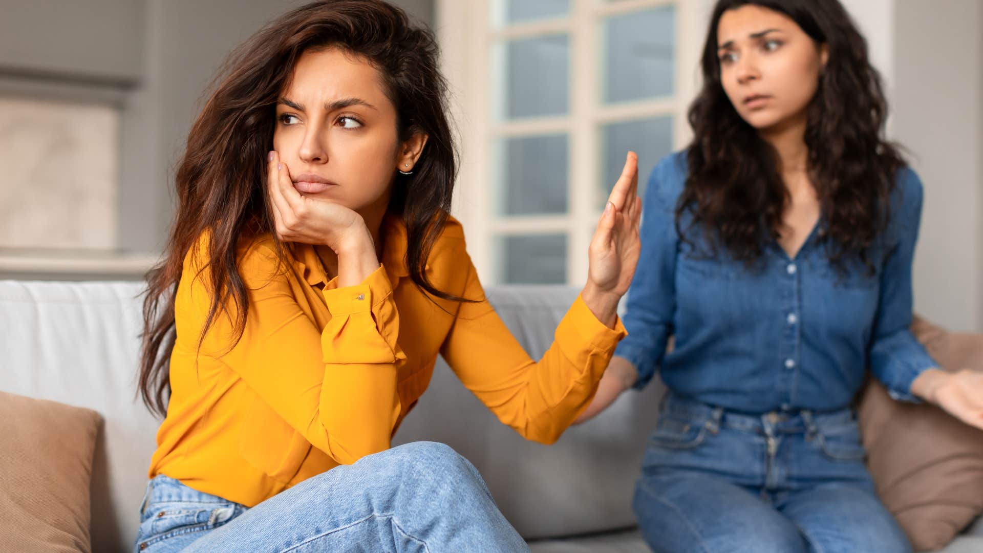 woman turned away from her friend who is concerned for her