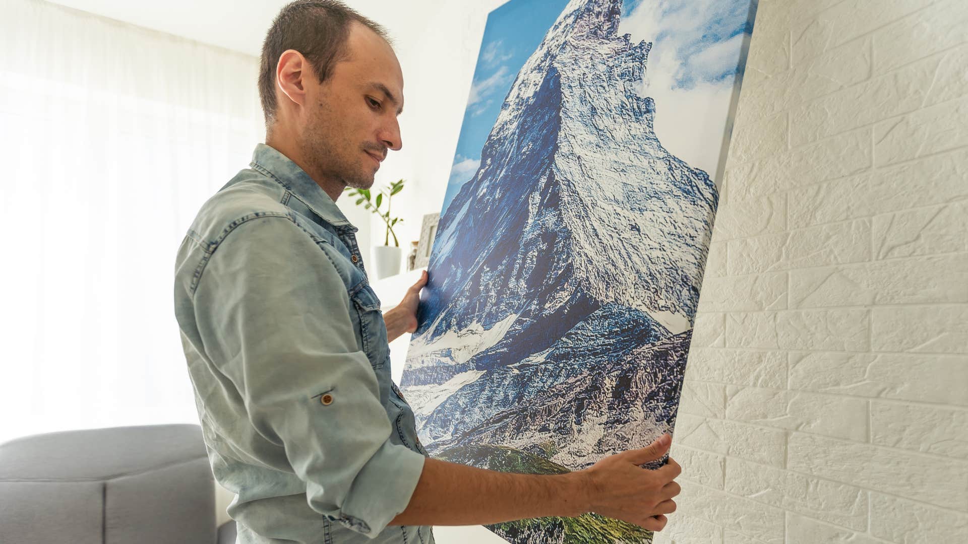 man hanging up gloomy artwork in his home
