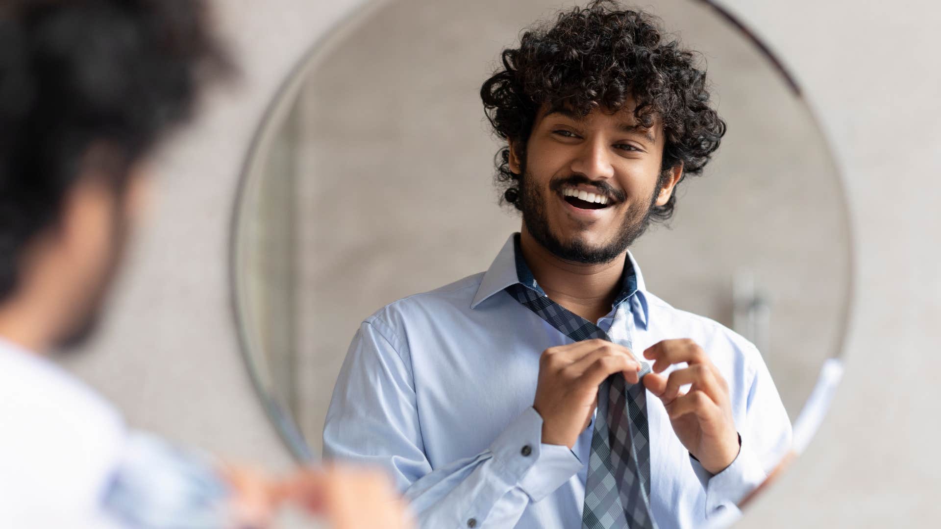 man smiling and looking in a mirror