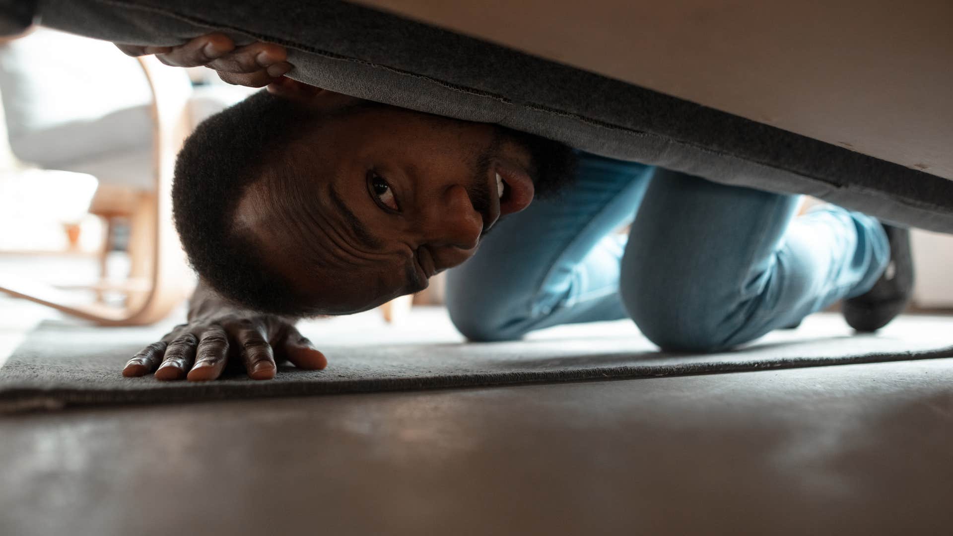 man looking under his bed for storage