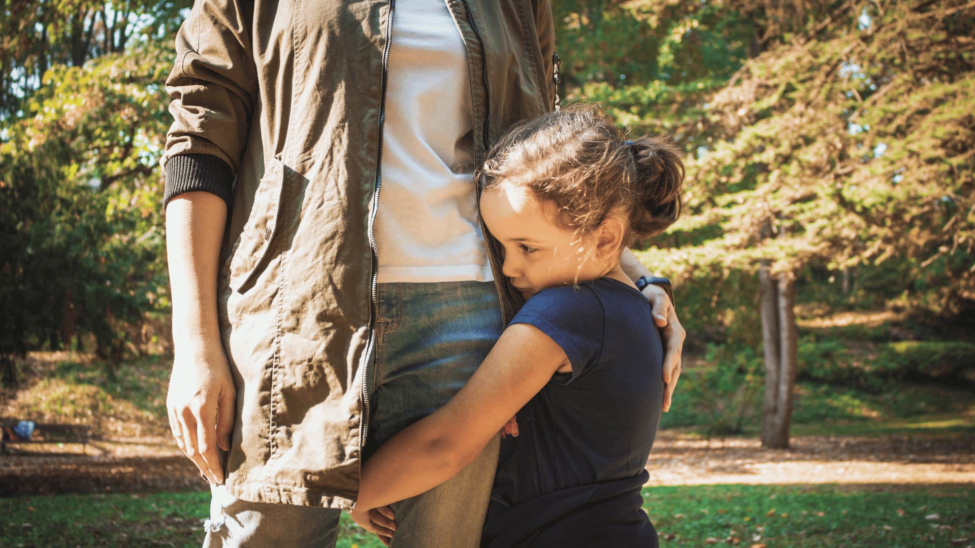 shy little girl hugging parent's leg