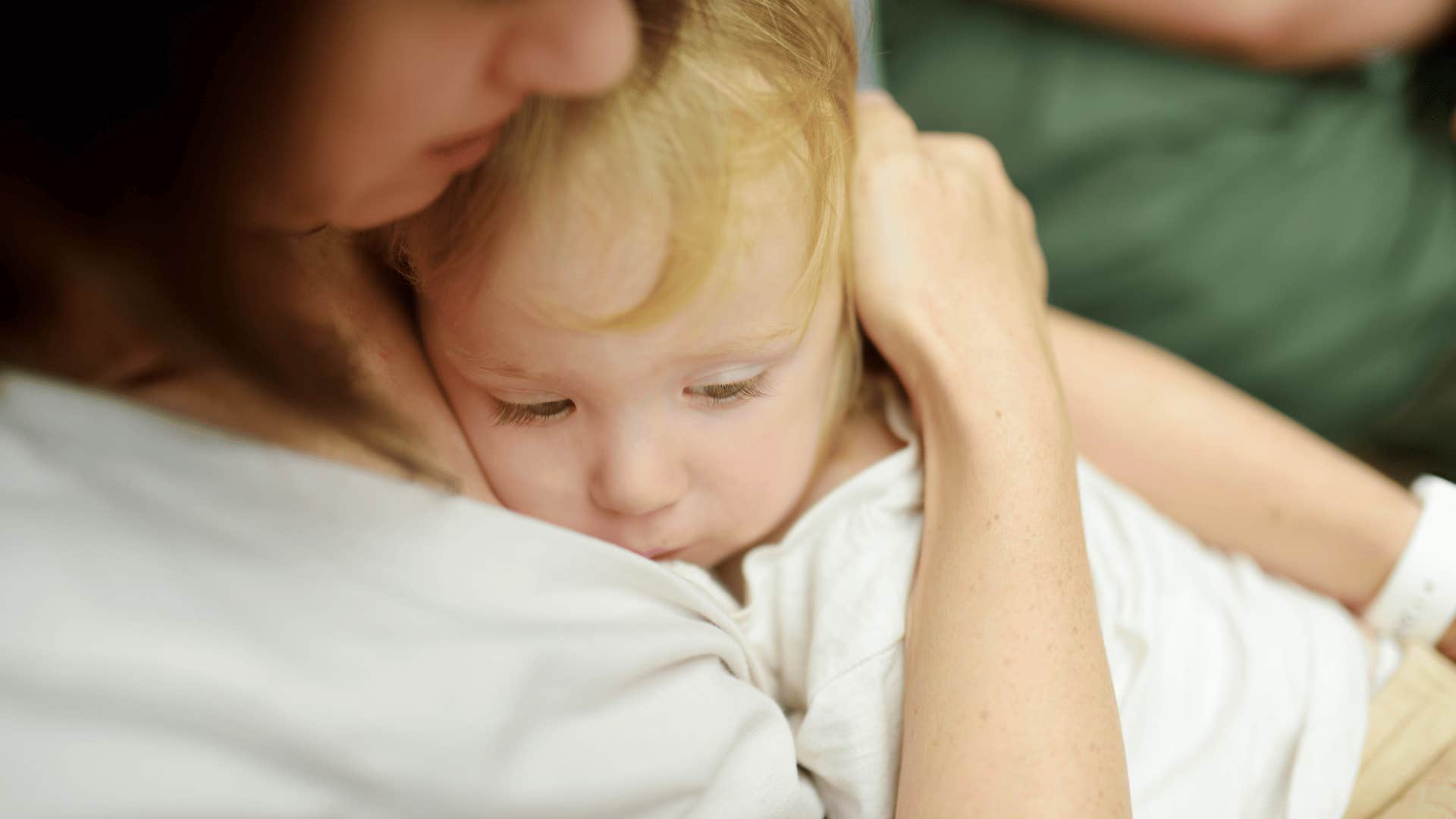 little boy being clingy and cuddling in mom's arms