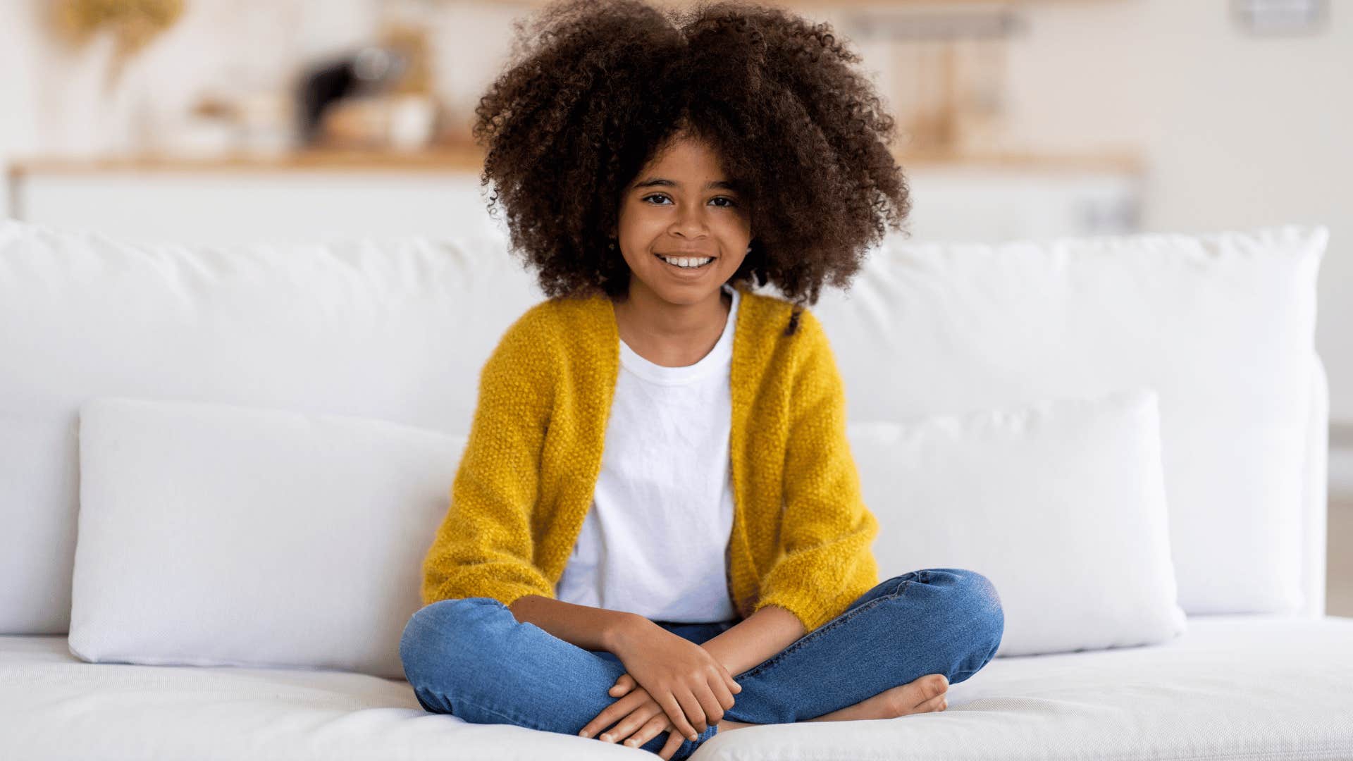 little girl sitting alone on couch
