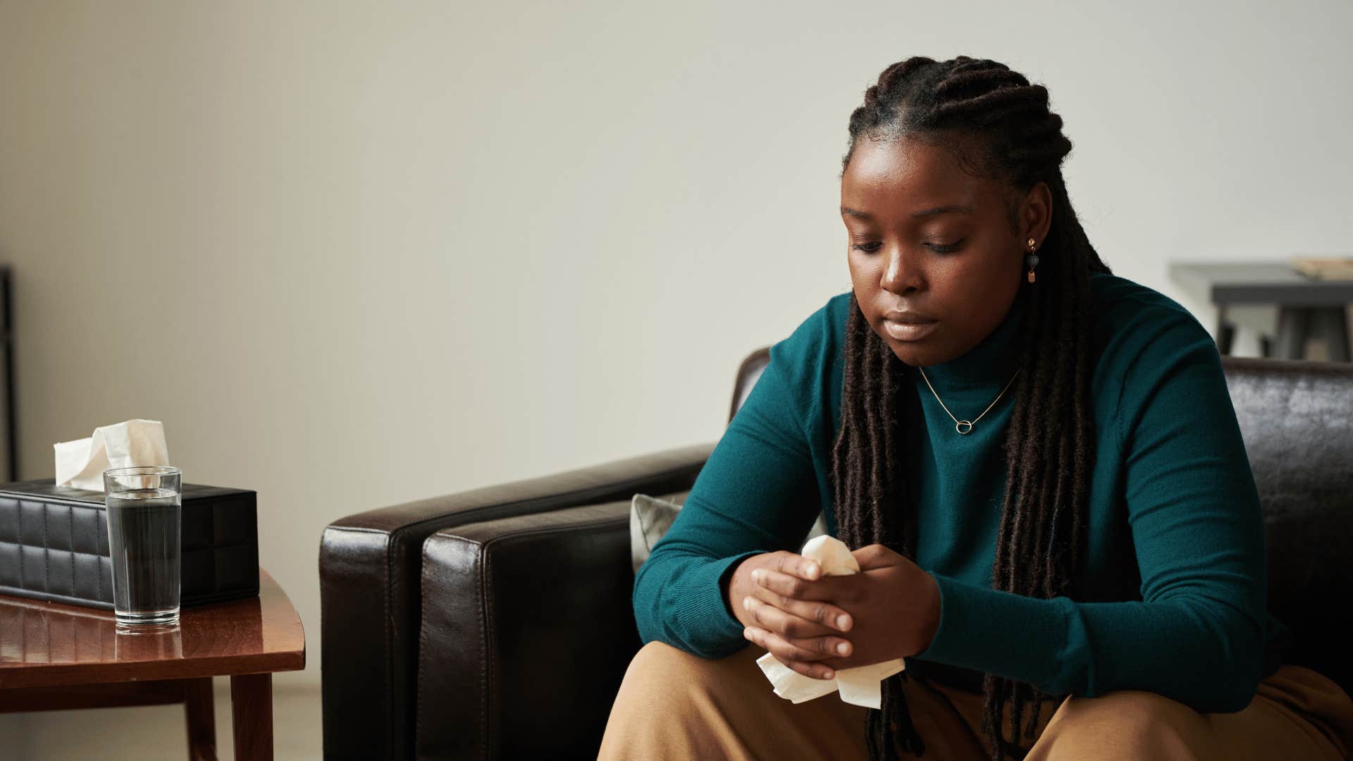 upset woman sitting on couch holding tissue