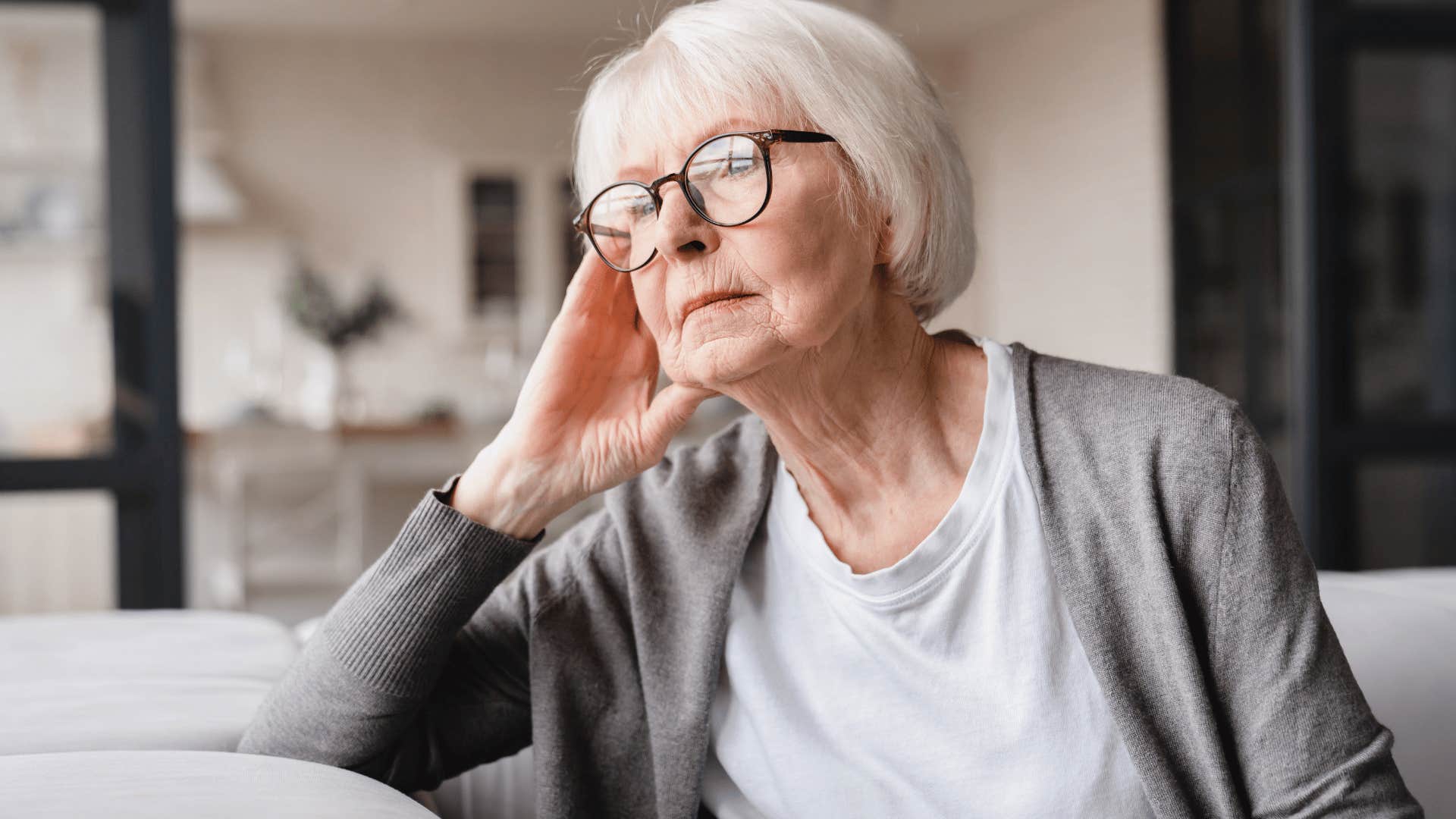 elderly woman sitting on couch looking out window