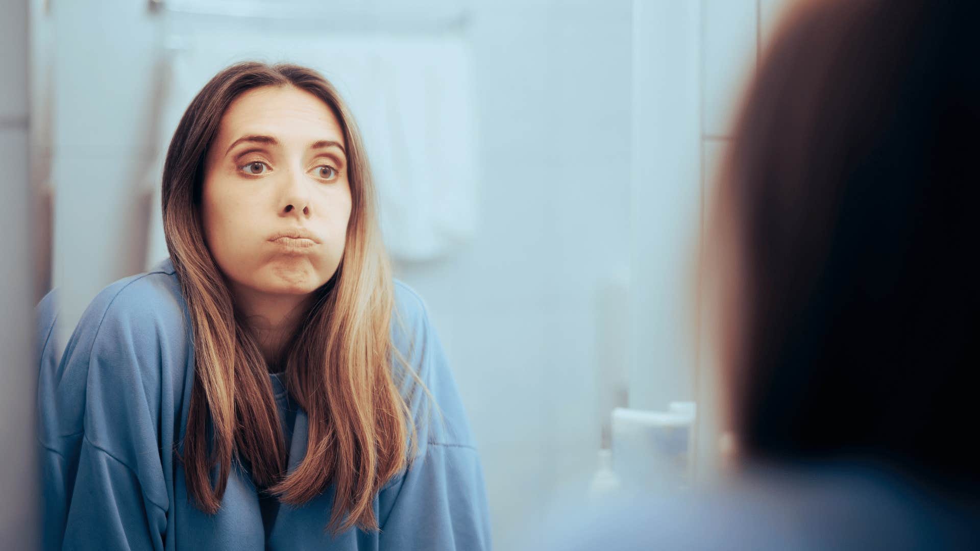 woman looking in the mirror feeling overwhelmed