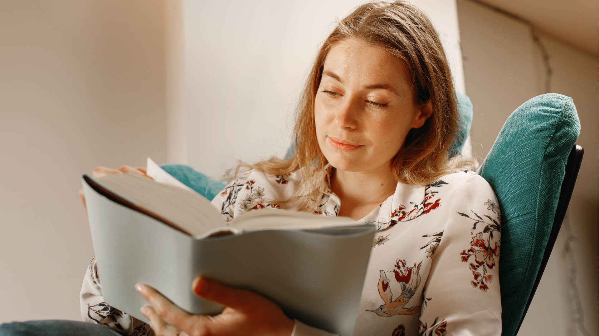 intelligent woman reading a book sitting in a chair