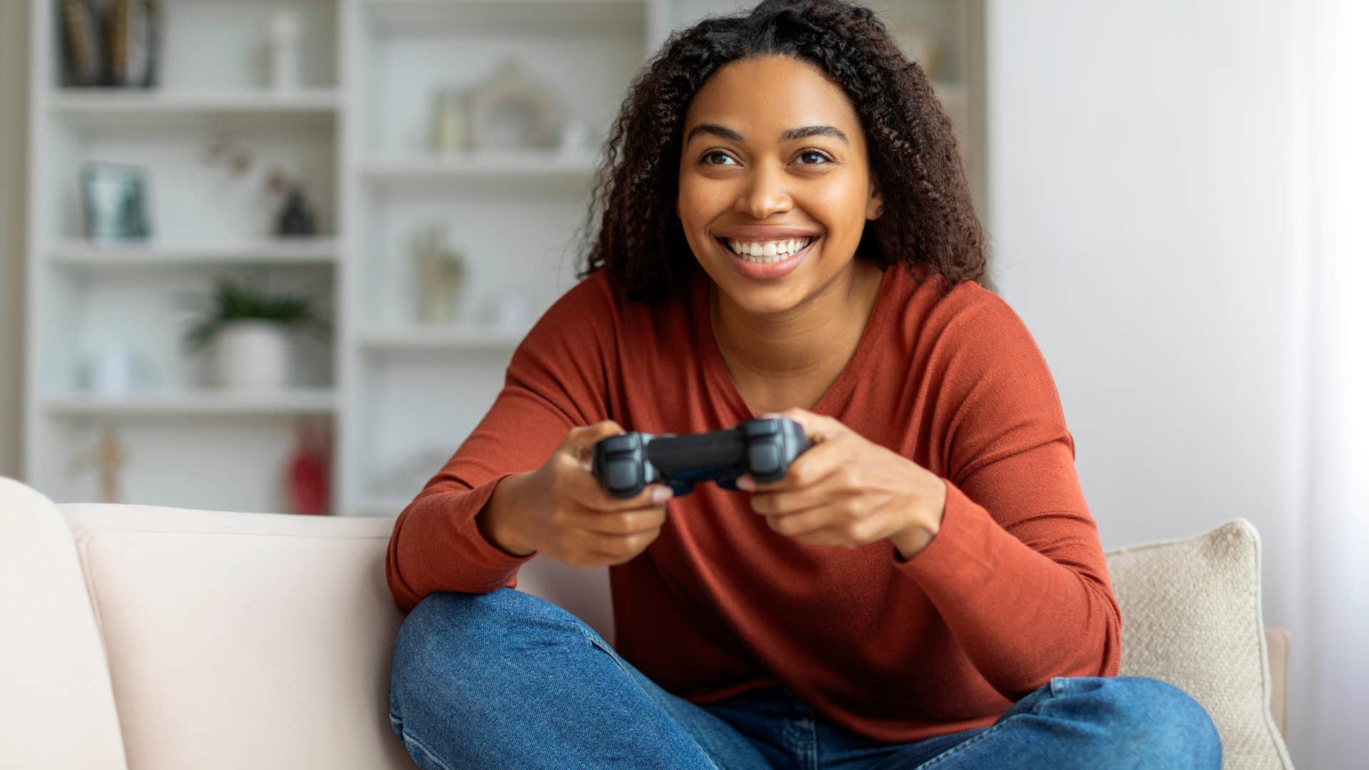 smiling woman playing video games on couch