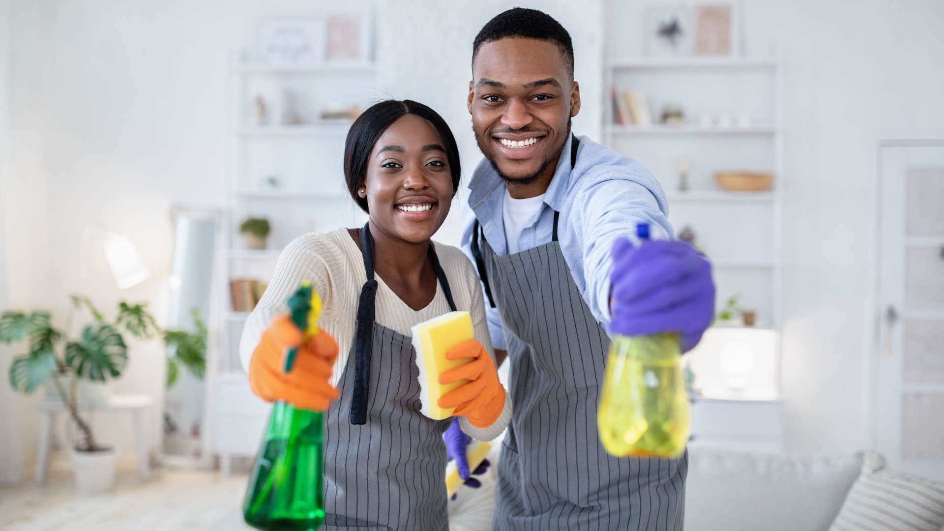 A husband gets ready to help his wife clean the house by holding cleaning products.
