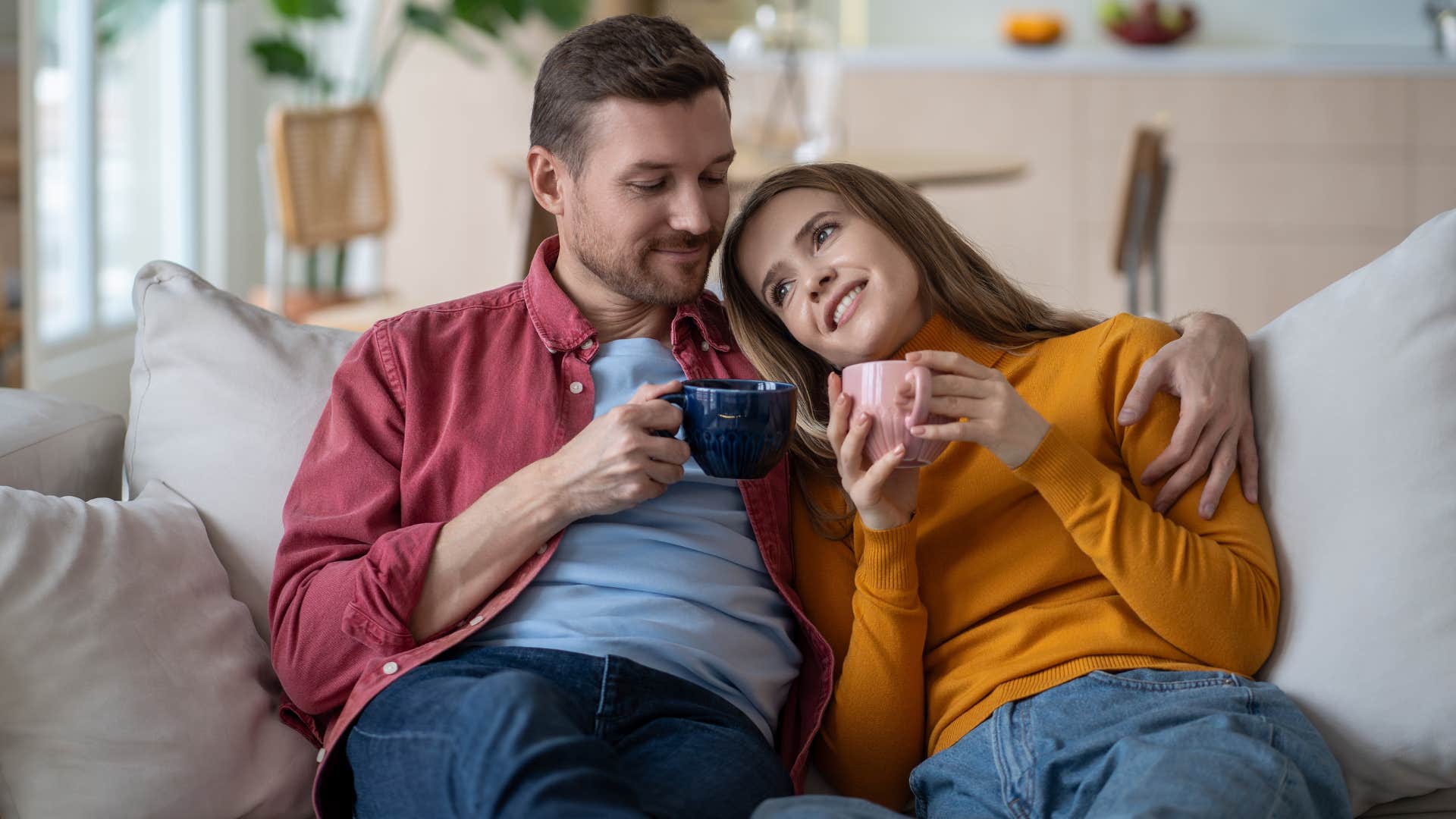 A husband actively listens to his wife as they relax on the couch.