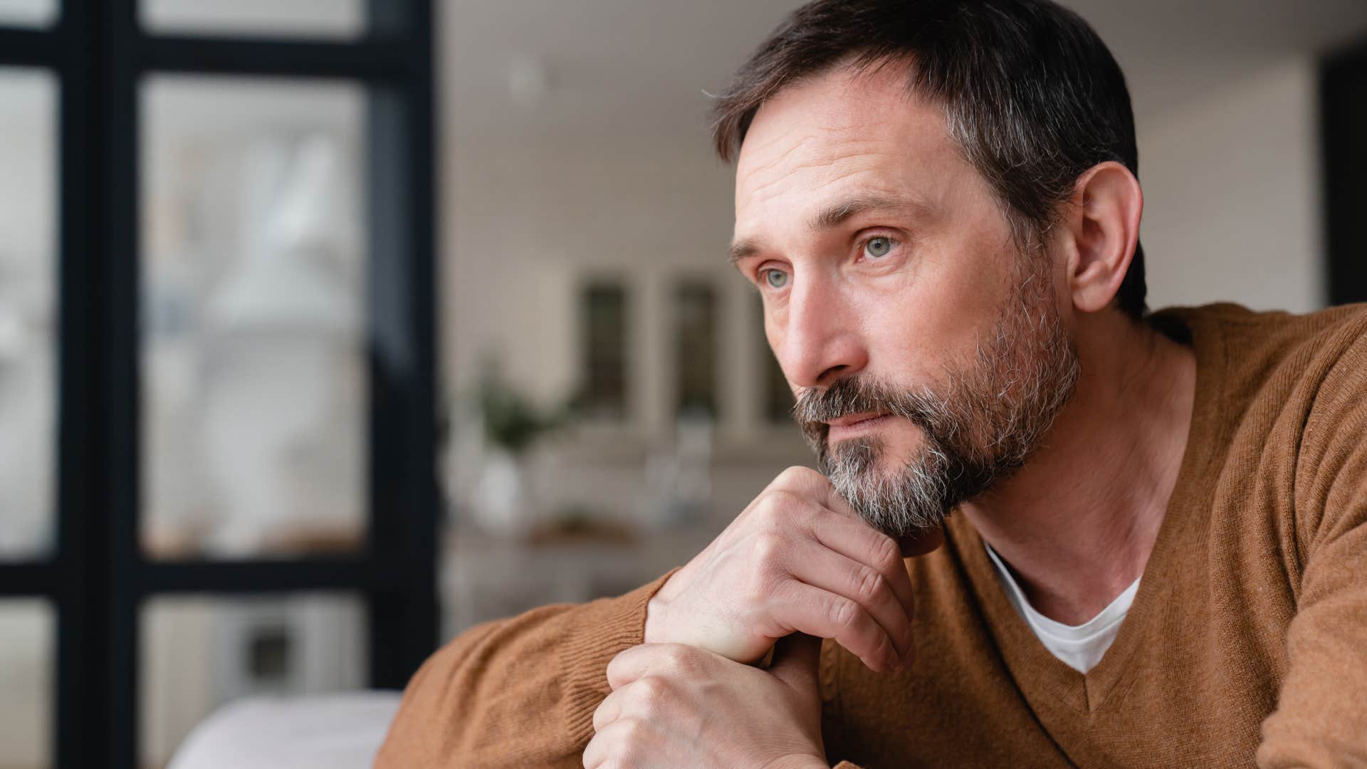 Man thinking "I guess I'm just a bad husband" while looking out a window.