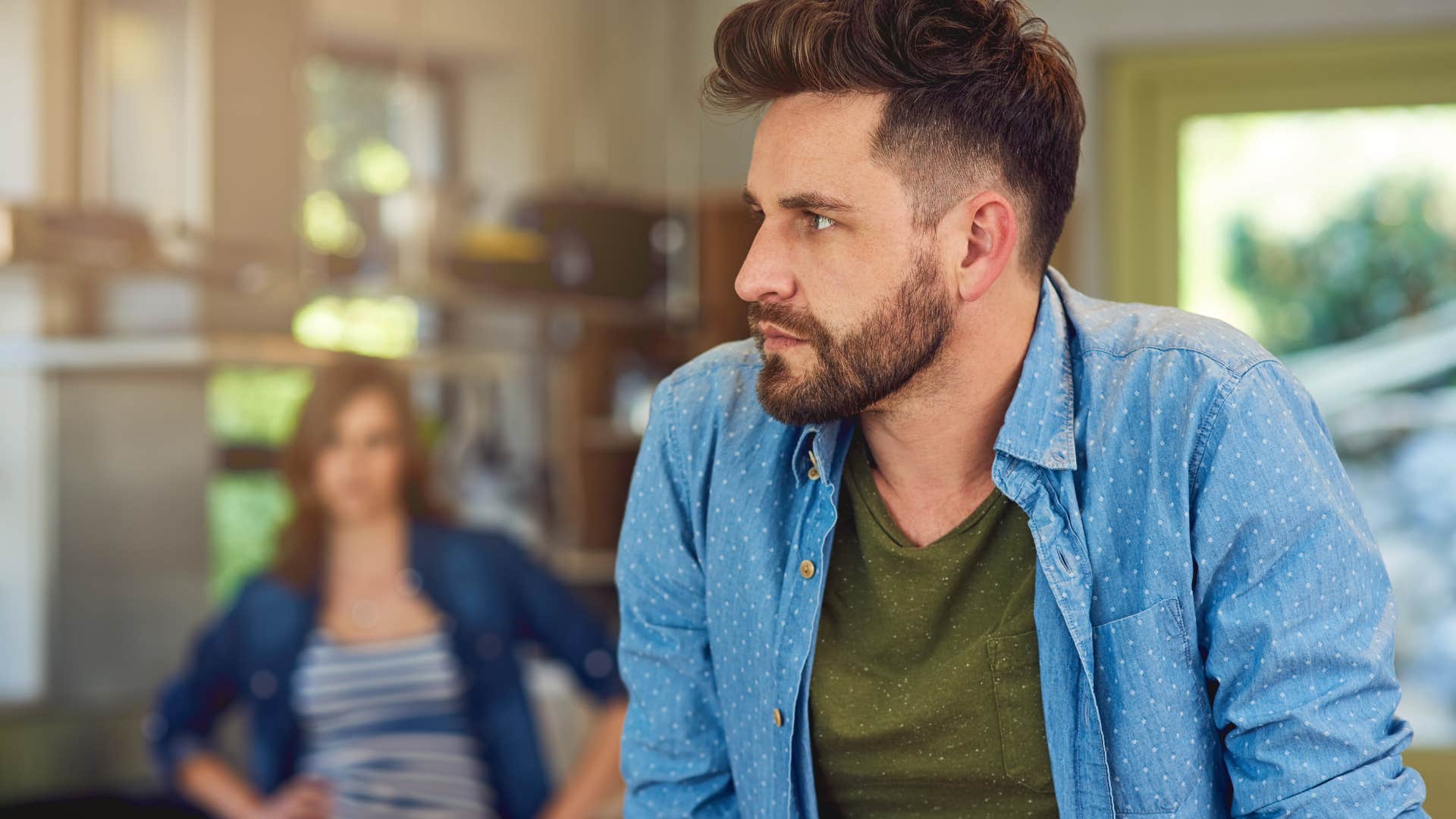 Man saying "you're overreacting" while turning away from his wife.