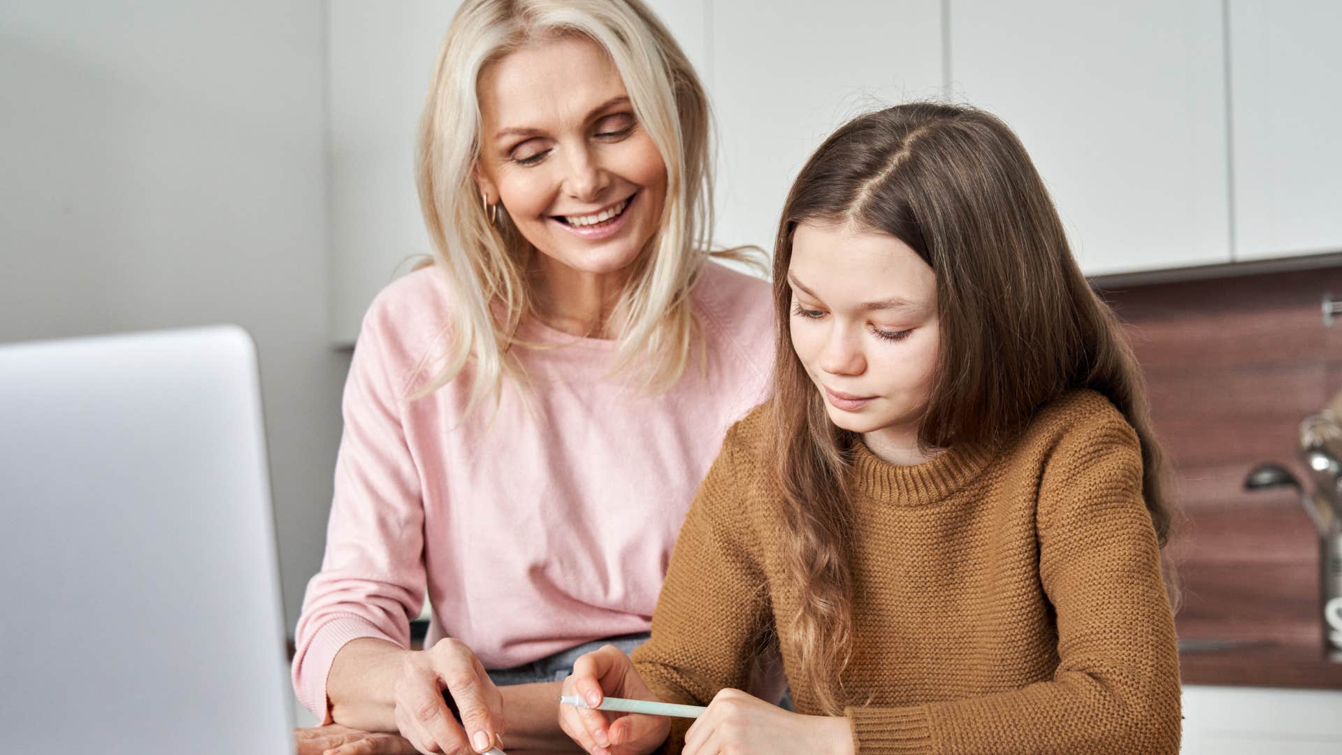 young girl getting help with homework from her mom
