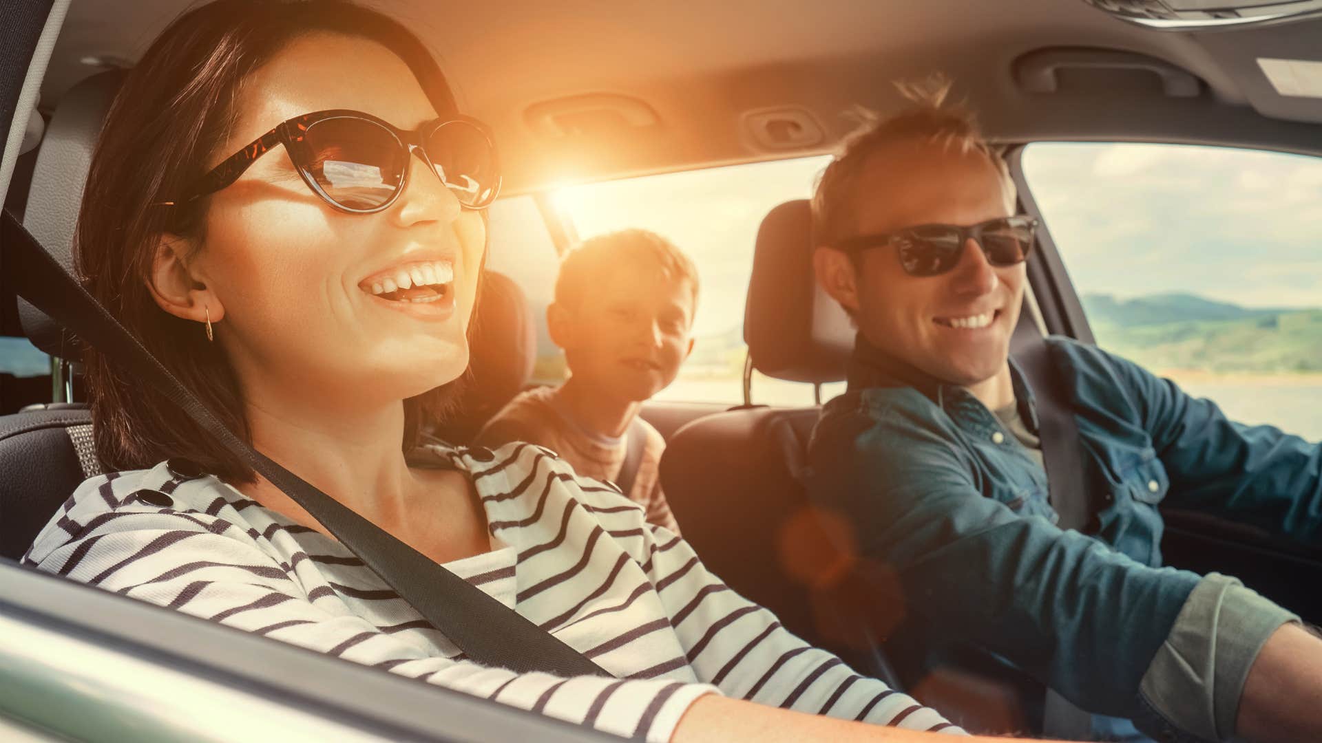 family smiling on a road trip in their car