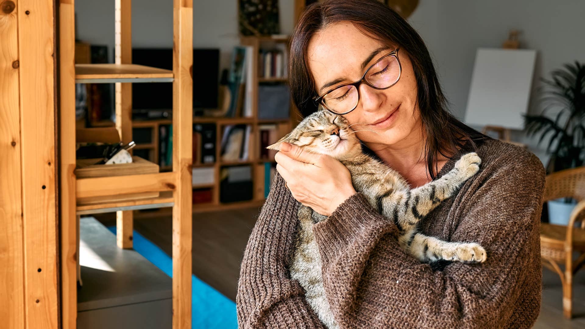 woman holding happy purring cat in her arms