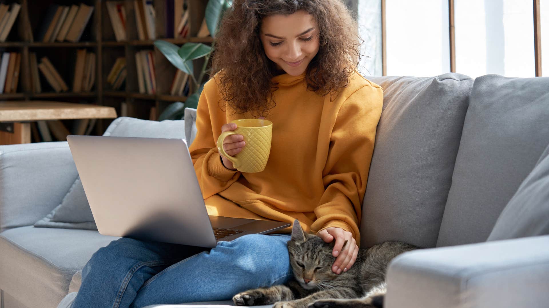 woman petting cat sleeping next to her