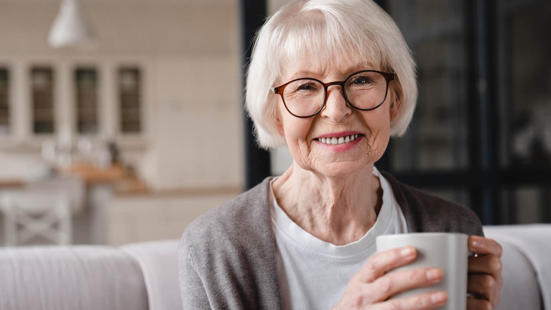 Woman who embraces solitude without judgement smiling and drinking coffee.