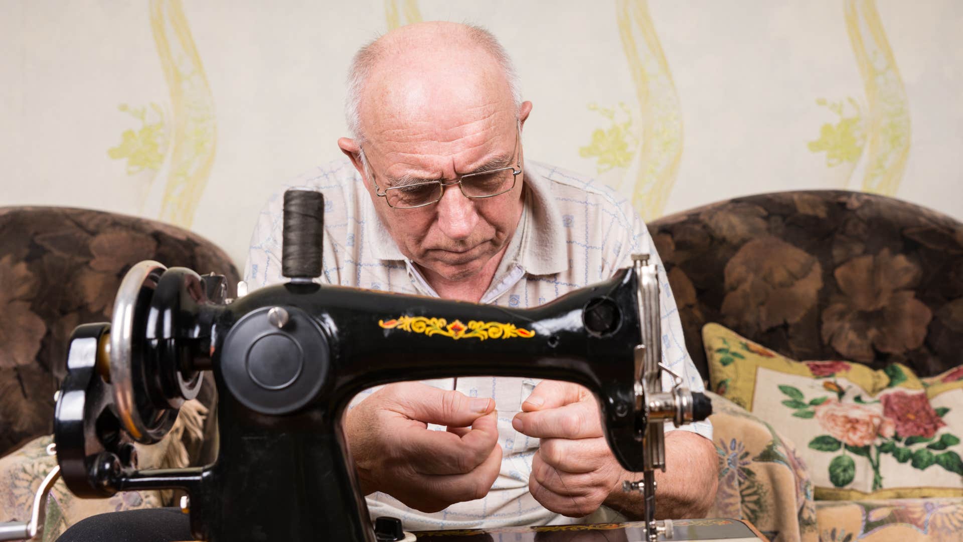 Agning man does sewing chore