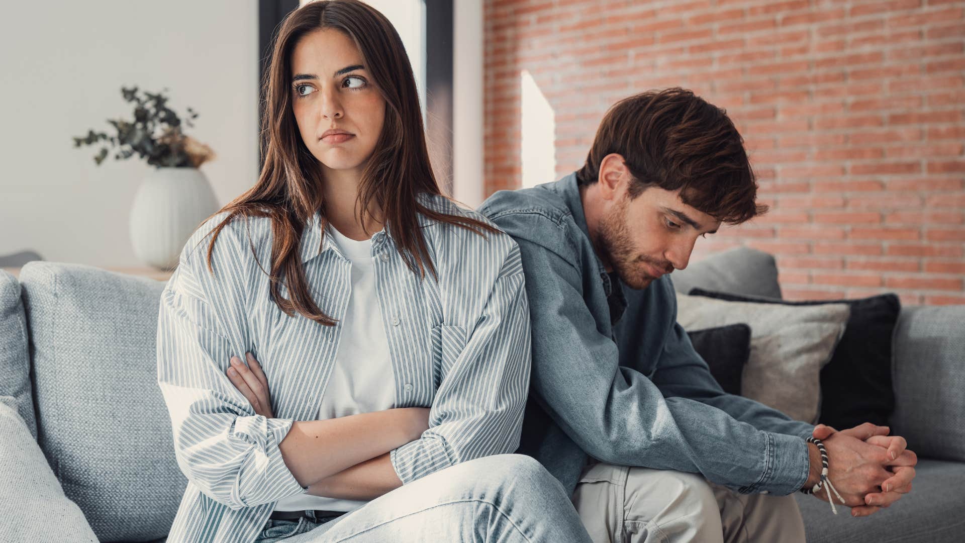 woman avoiding eye contact with her upset partner on the couch