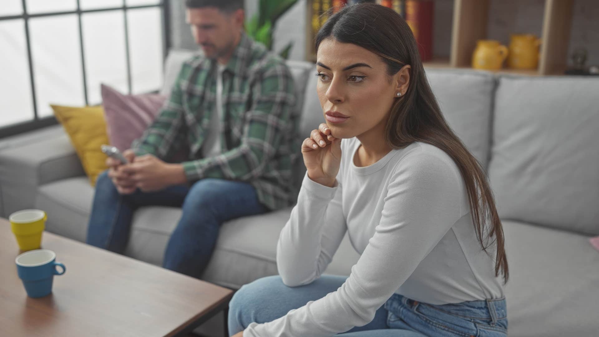 man fidgeting turned away from upset woman