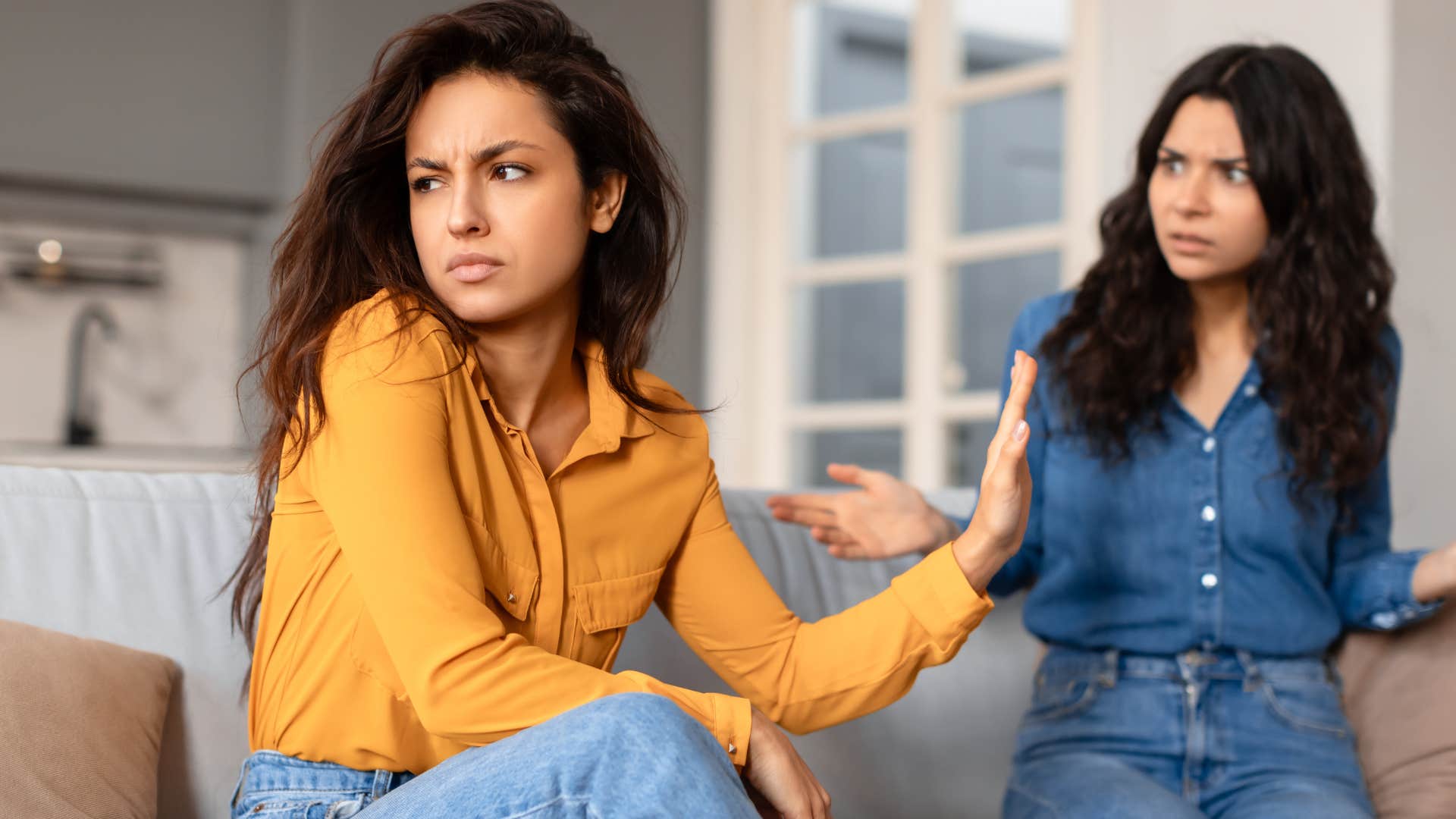 woman with tense jaw rudely turned away from friend