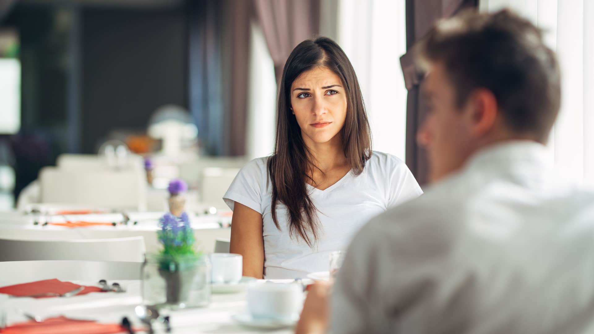 a woman looks at her boyfriend sadly after he talked down to their server