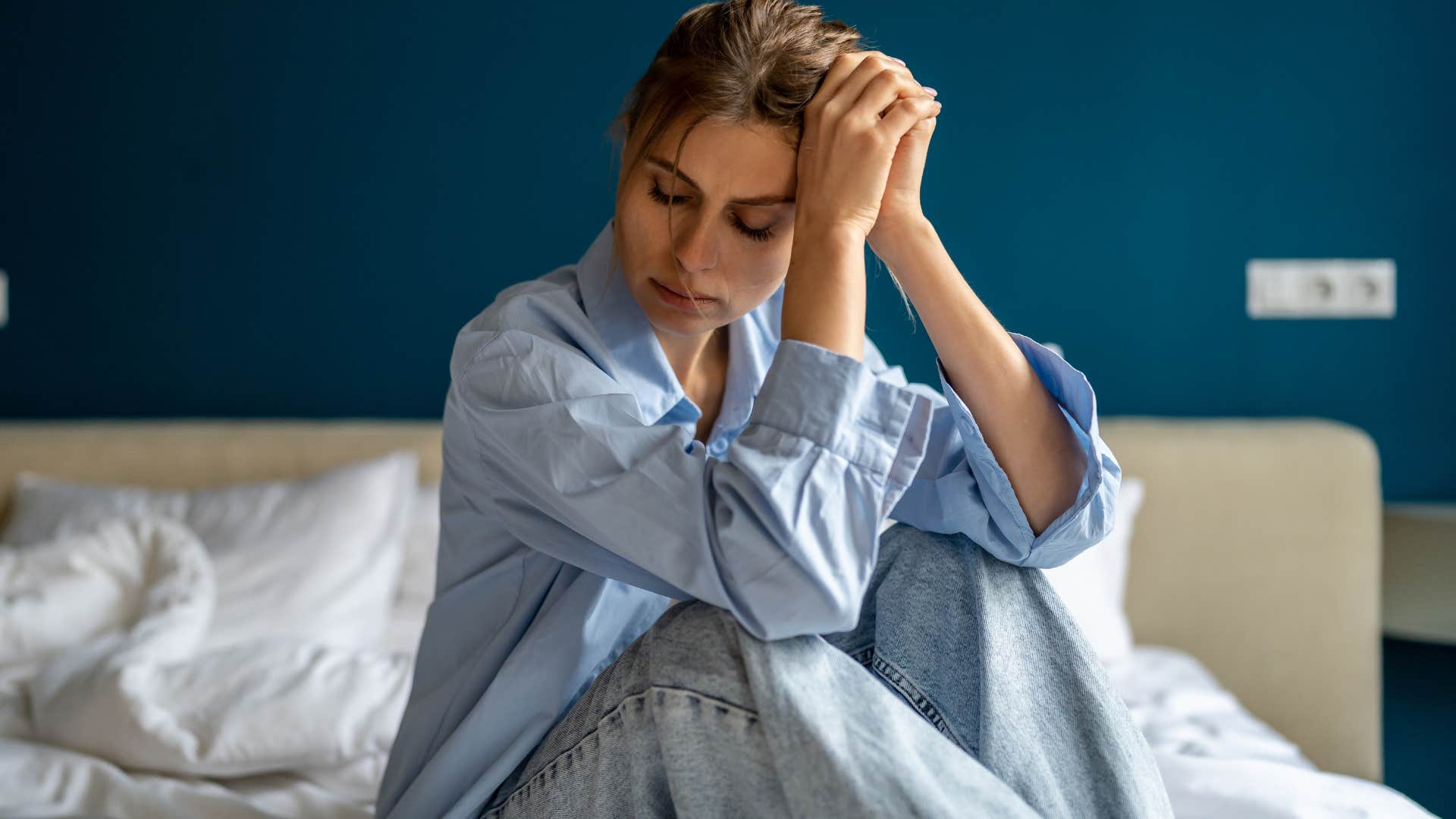 tired woman sitting sadly on her bed