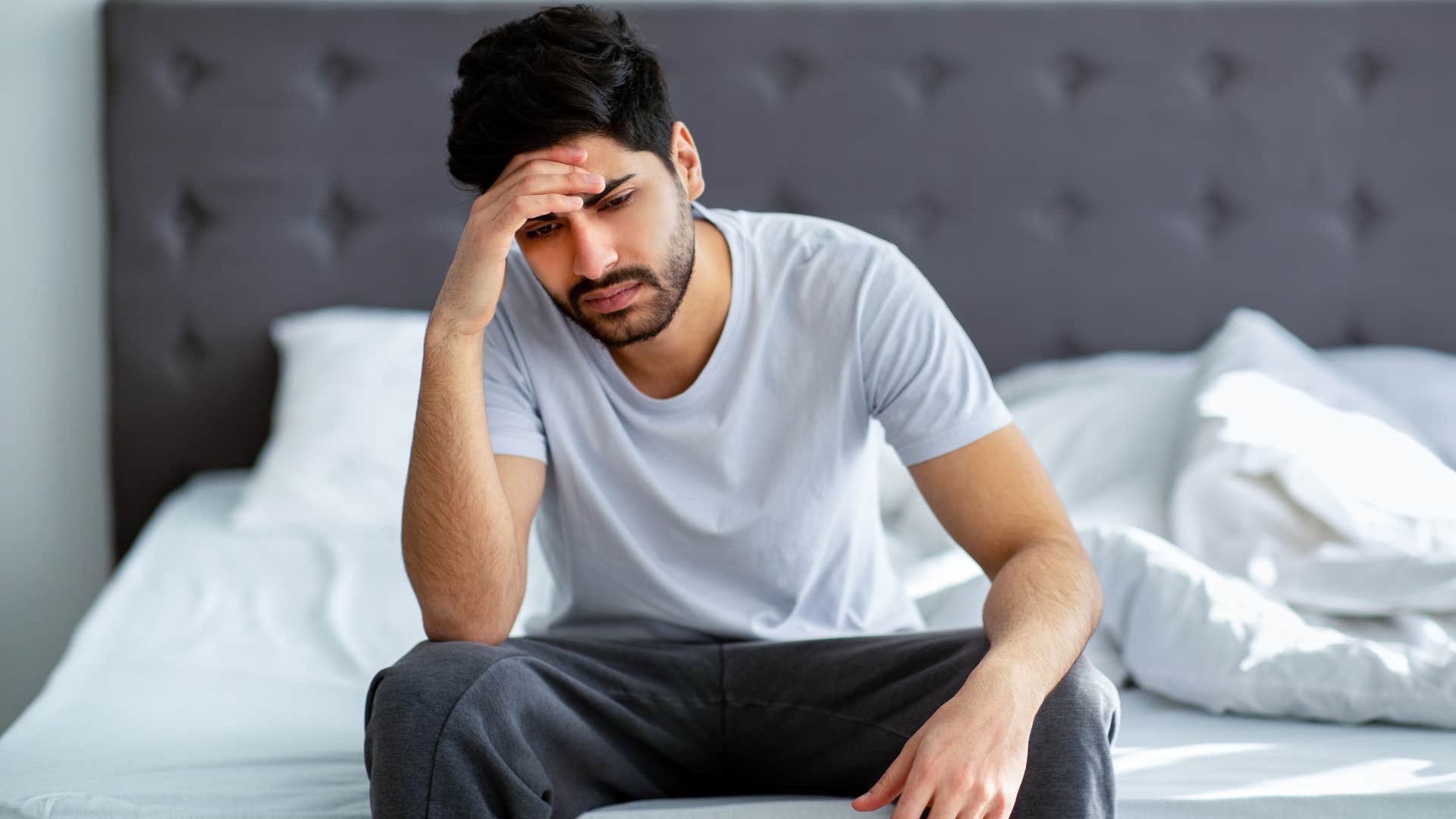 man sitting on bed waking up tired