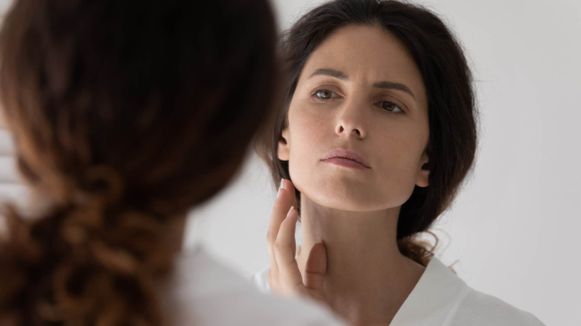 woman looking in mirror after weight fluctuation