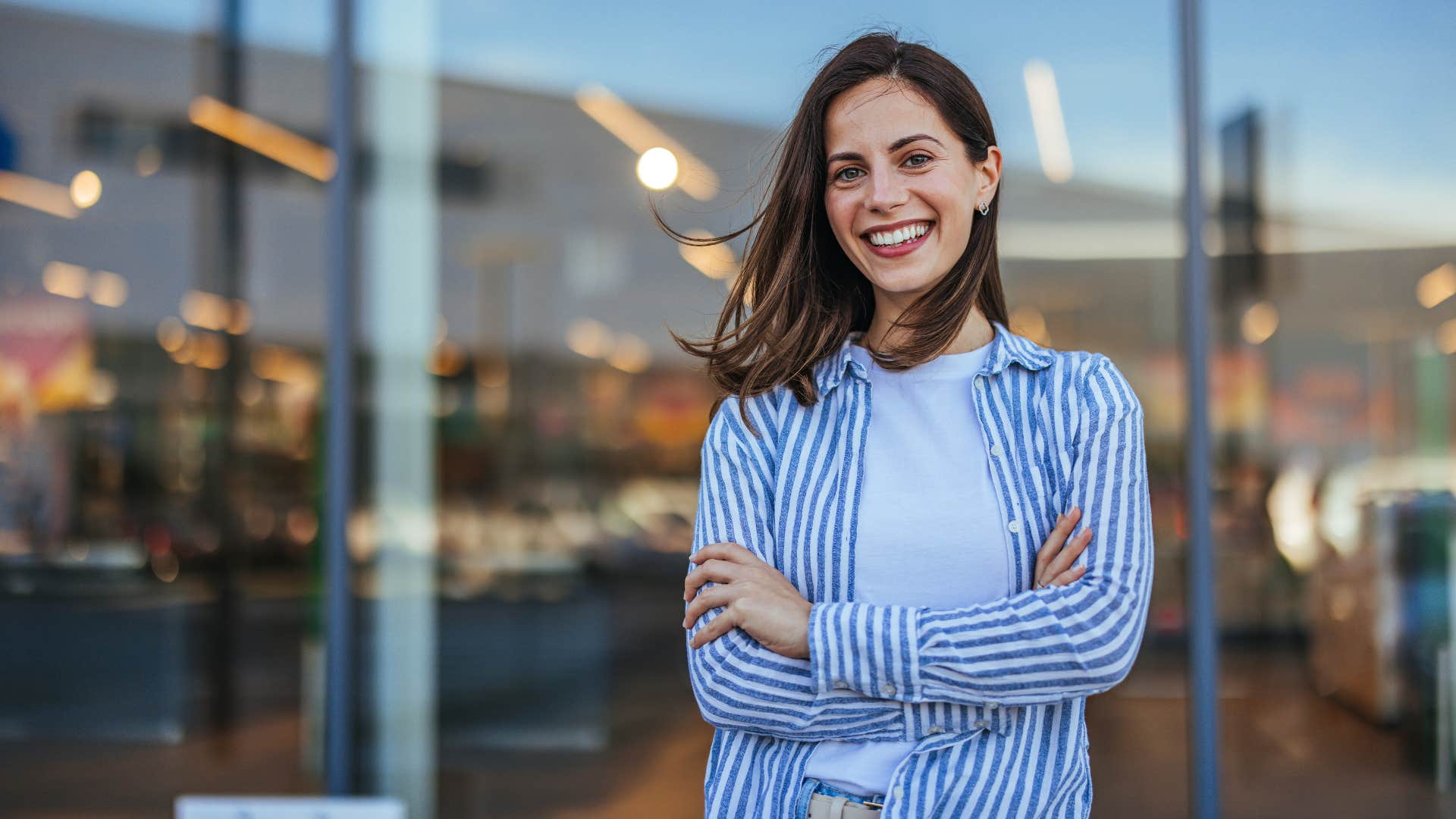 woman in stripped jacket not allowing her failures to define her as she crosses her arms and smiles at camera confidently 