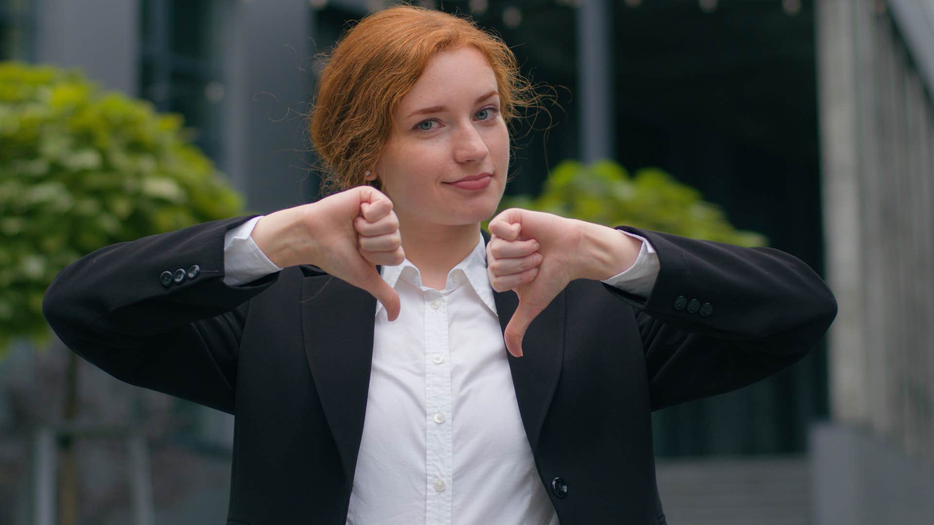 woman in black jacket and red hair putting thumbs down as she realizes that saying no is a full sentence
