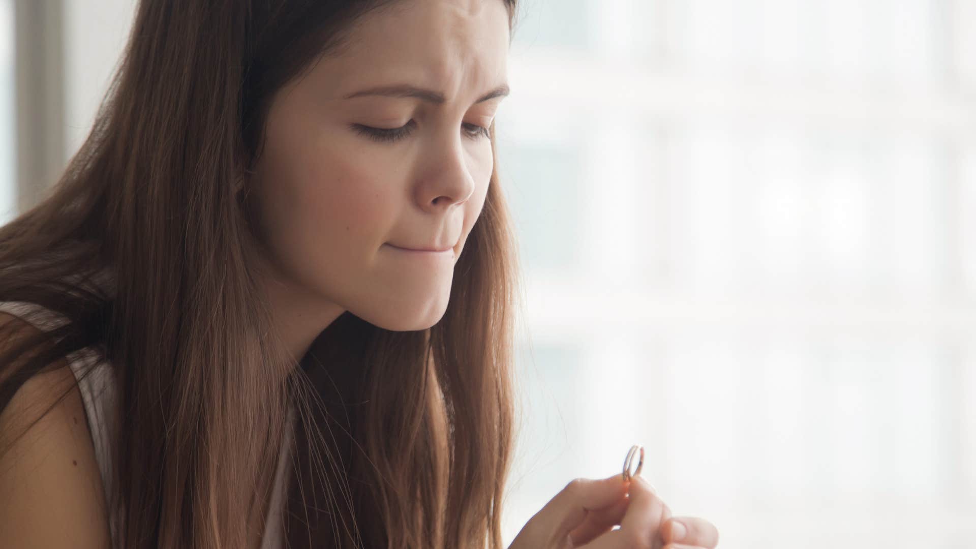 woman feeling guilty for marriage fights holding wedding band