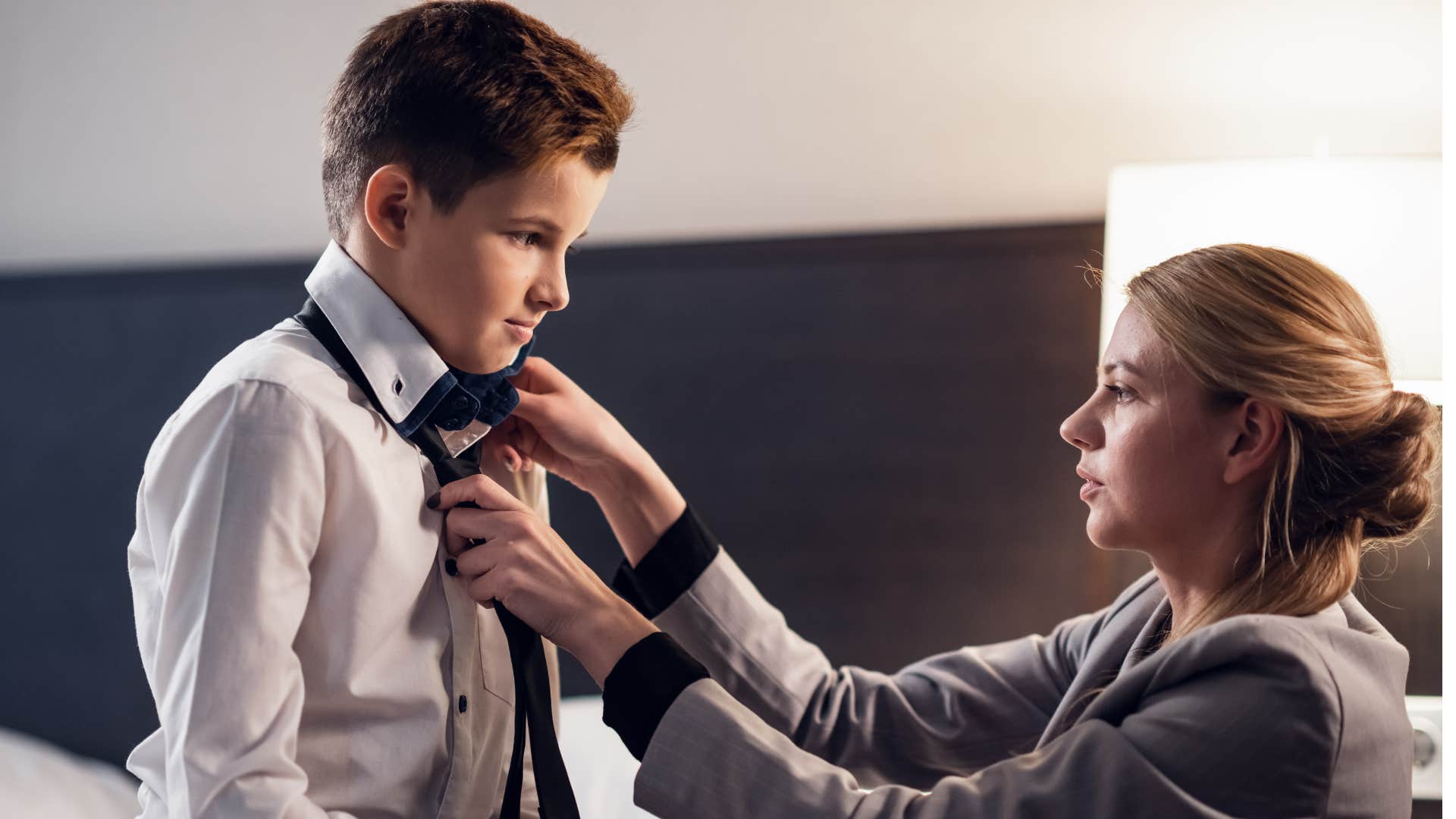 mom getting young son dressed in his suit