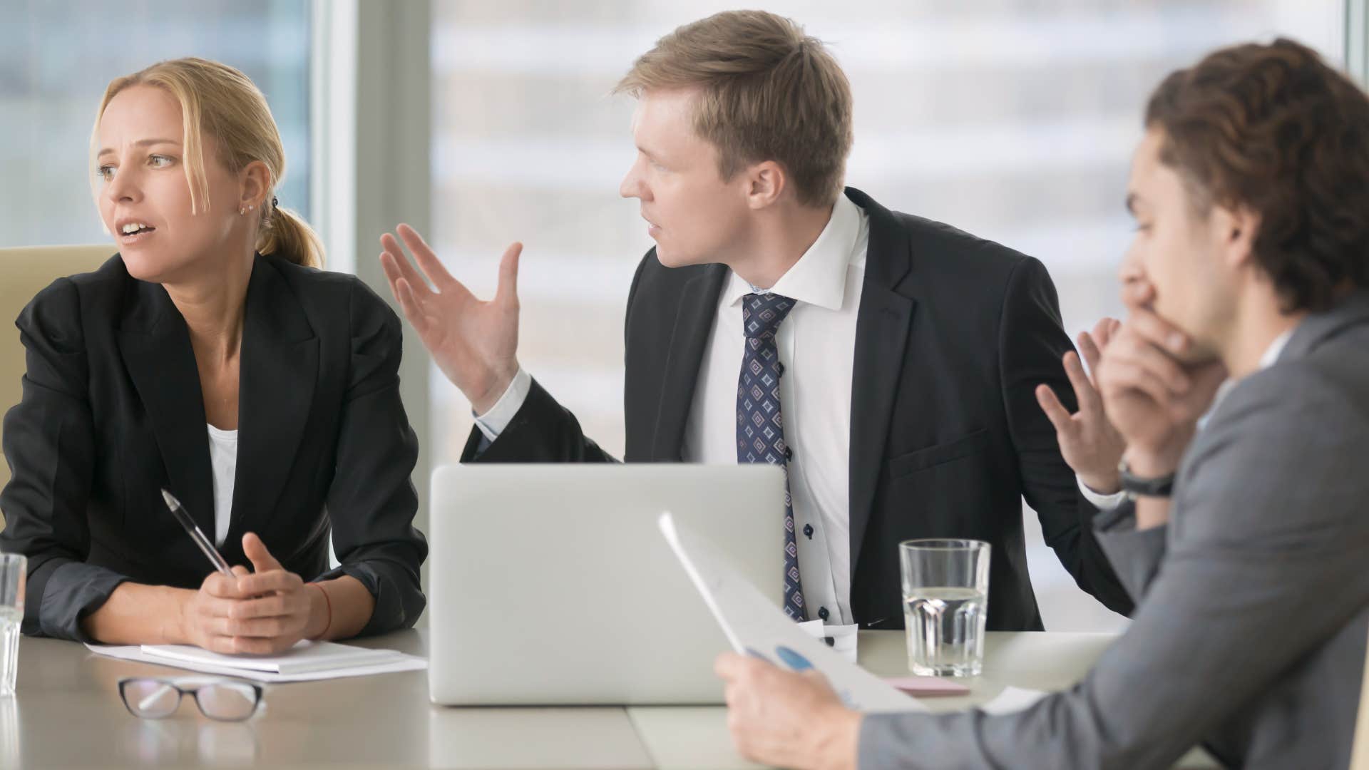 man who sees the negative side of things arguing with coworkers as workers look tense