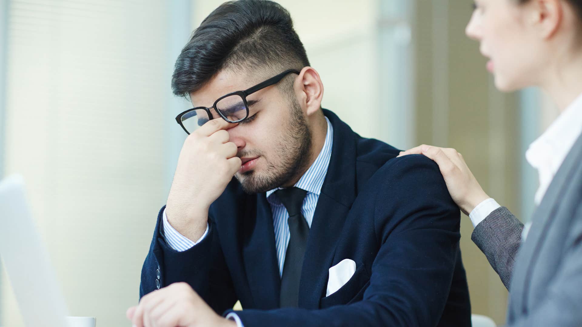 man in suit having a constant need for reassurance as woman coworker comforts him
