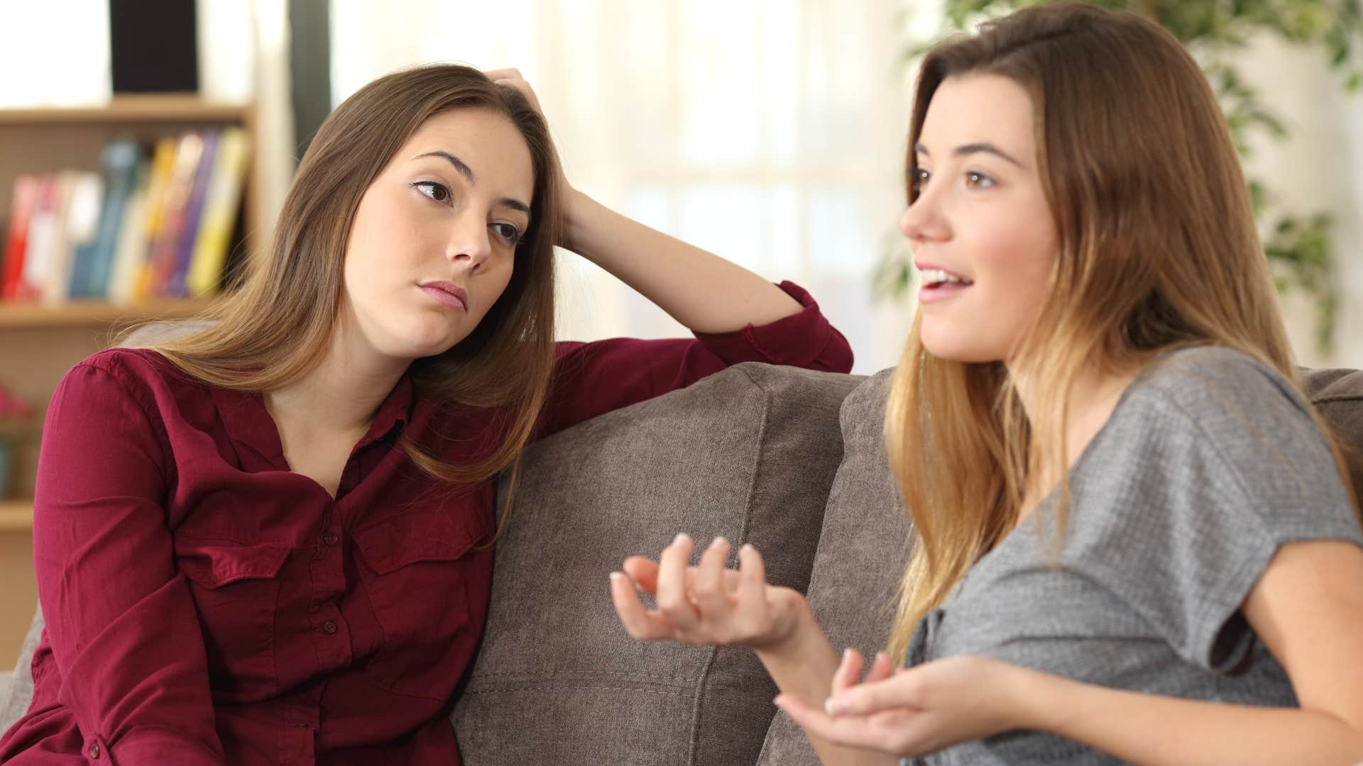 woman in gray shirt talking as woman in red shirt stares at her annoyed as she's engaging in a one sided conversation