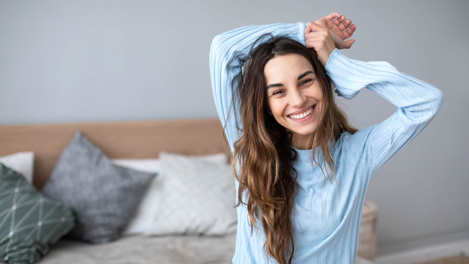 woman in her comfiest pajamas stretching in bed