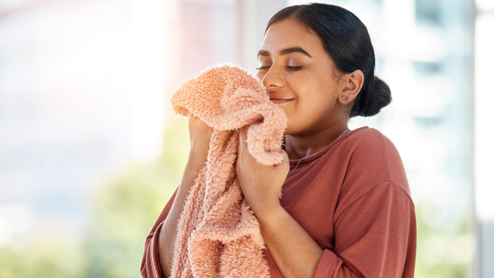 woman smelling fresh sheets to put on the bed